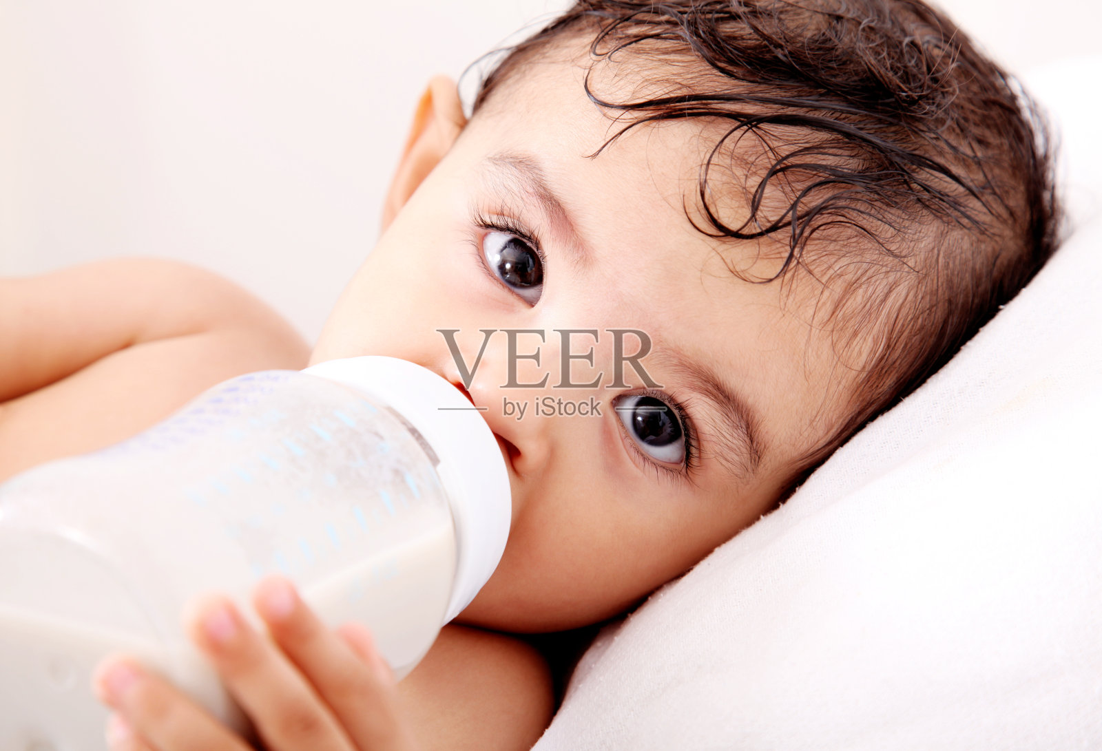 用奶瓶喝牛奶的黑头发婴儿照片摄影图片