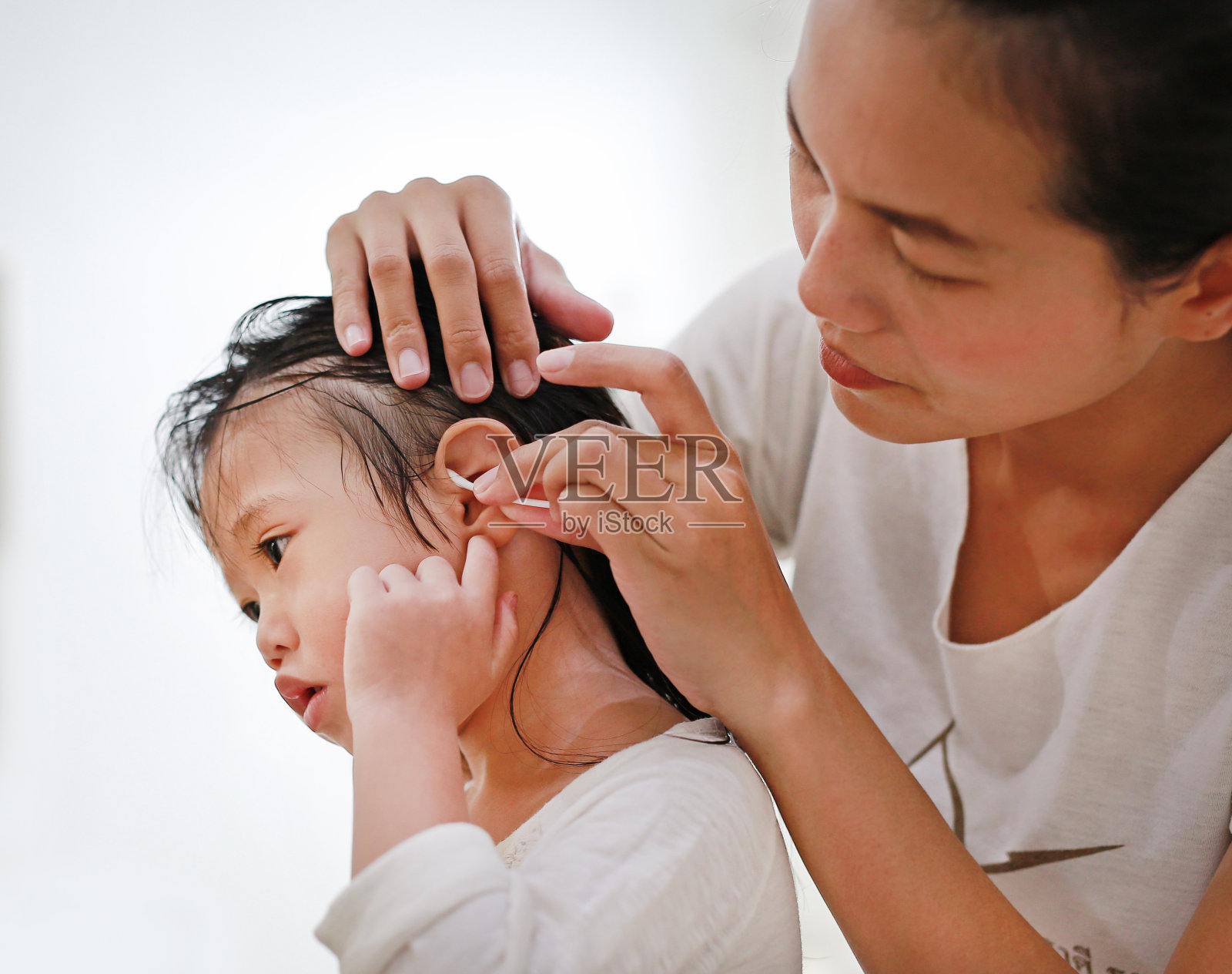 沐浴后的婴儿护理(妈妈清洁孩子的耳朵)照片摄影图片