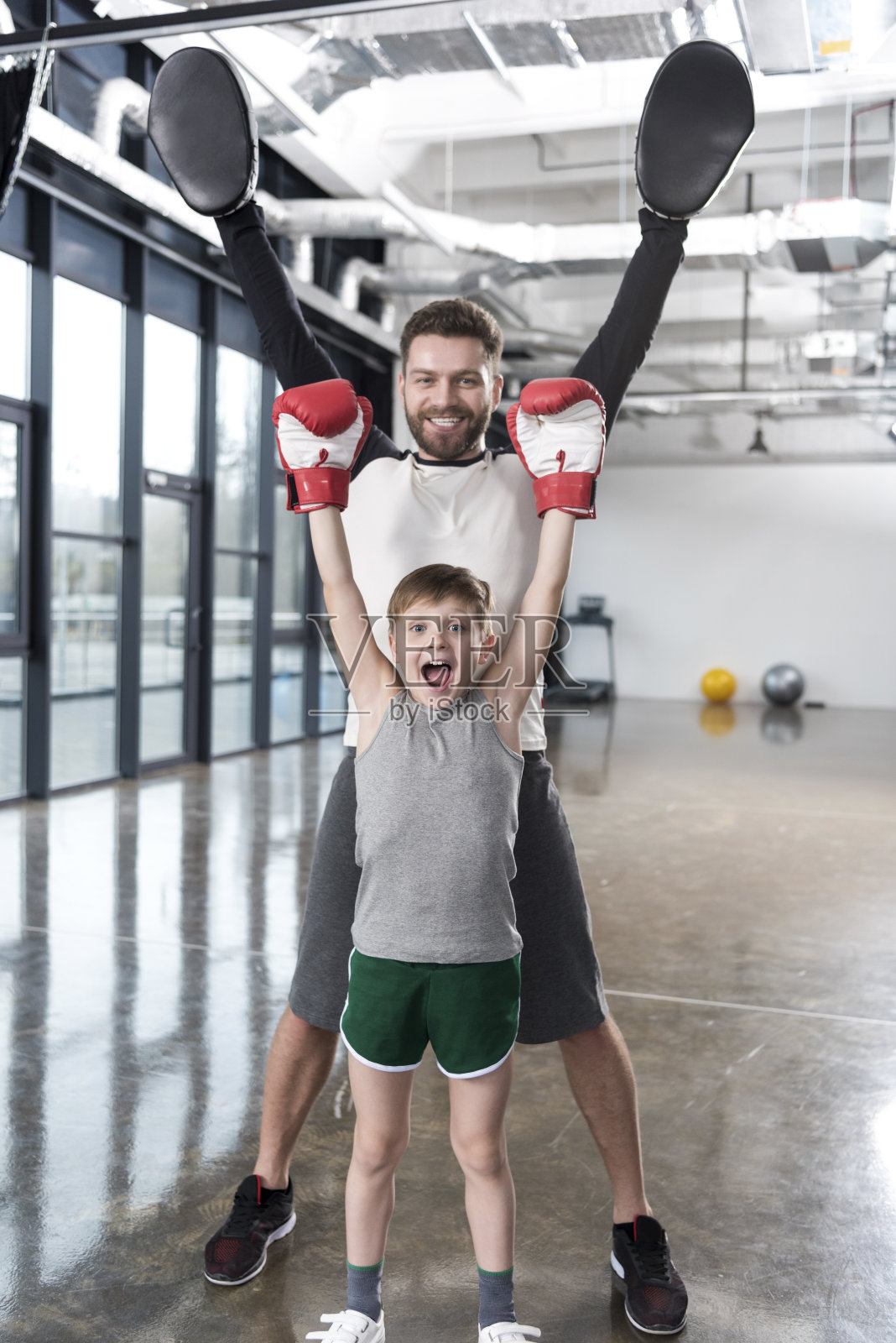 兴奋的小男孩拳击手和他的教练在训练照片摄影图片