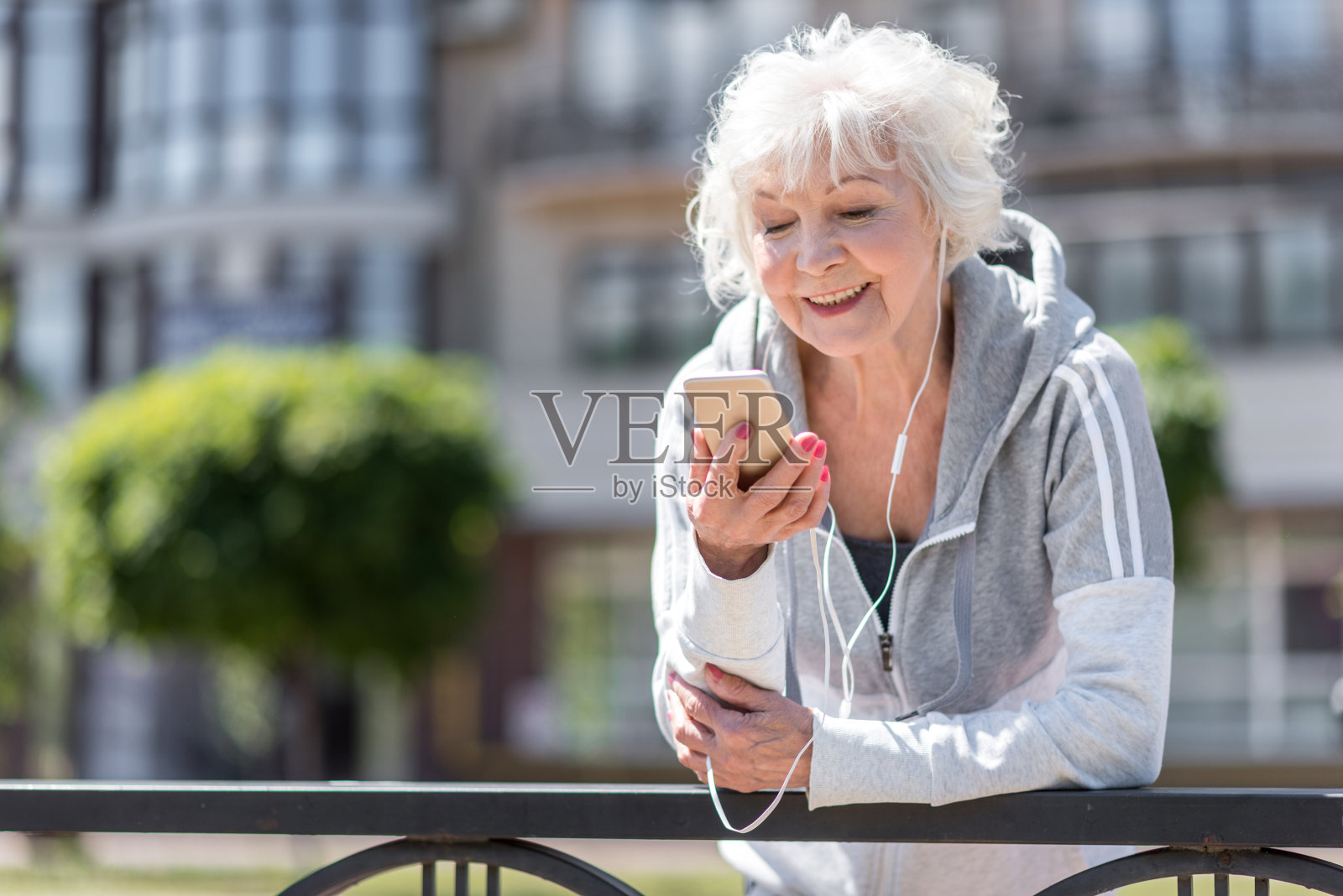愉快的老妇人通过耳机听音乐照片摄影图片