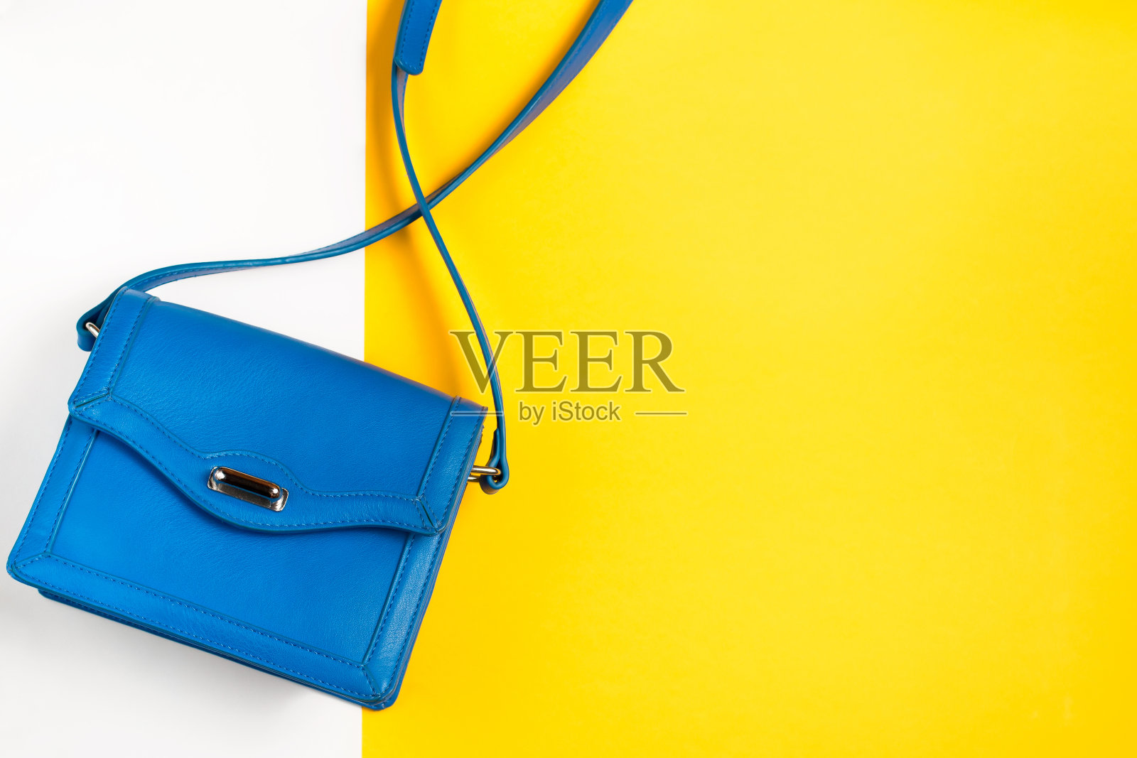 彩色背景上的女人钱包。蓝色和黄色柔和的颜色，俯视图照片摄影图片