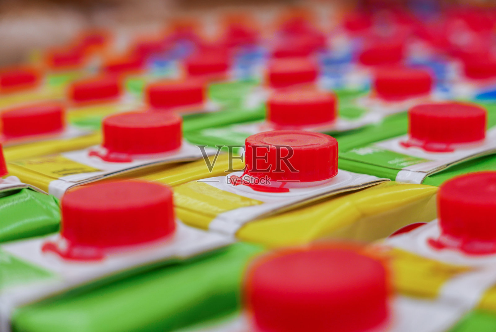 超市货架上有红色螺旋盖的彩色果汁盒。照片摄影图片