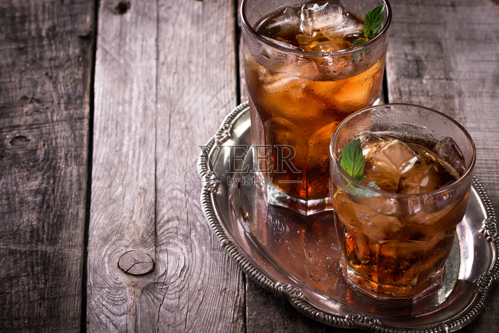 glass of cola, ice tea or with cubes, and mint garnish, on wooden table, alcohol drink照片摄影图片