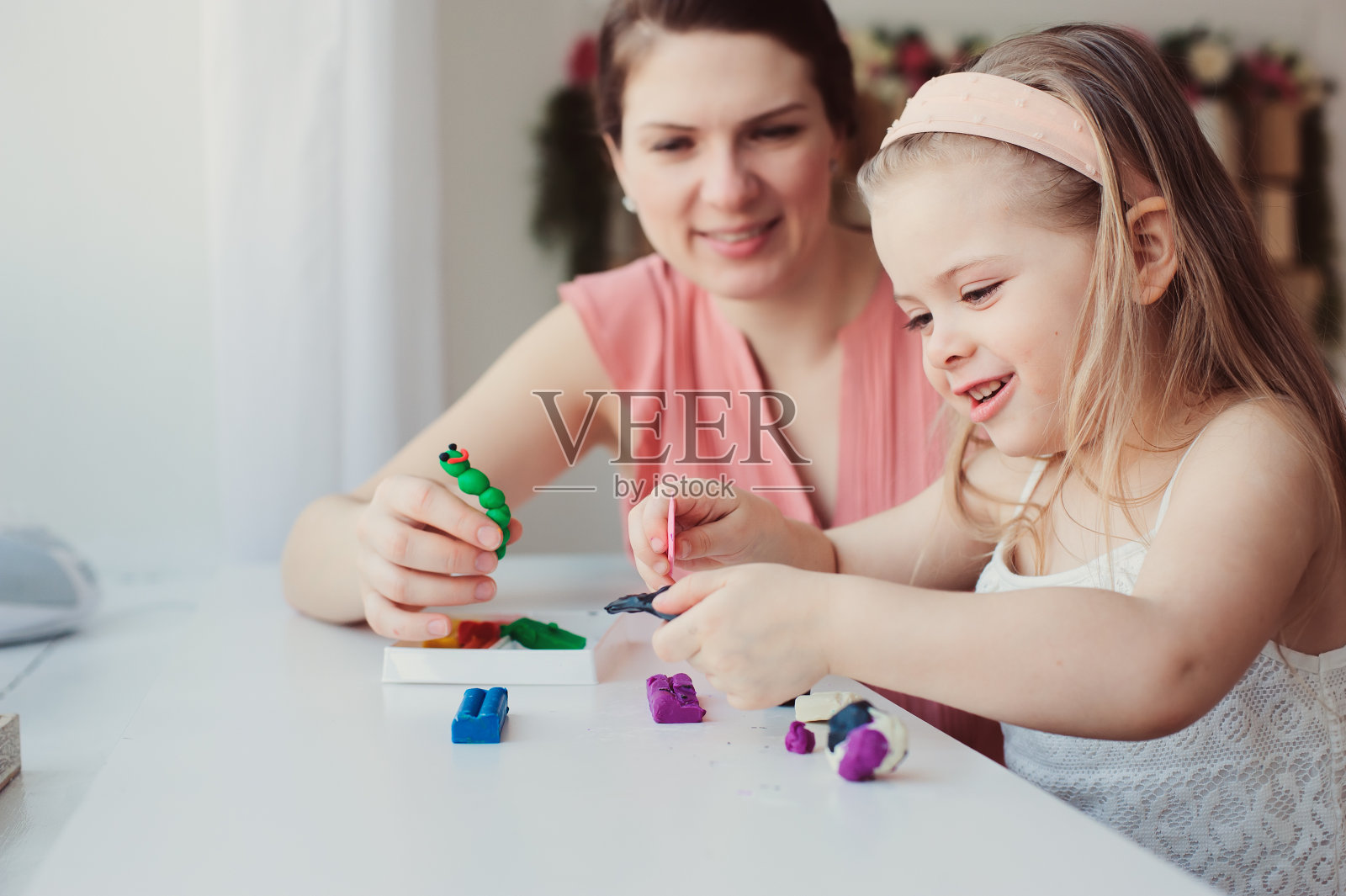 母亲和蹒跚学步的女儿在家里玩橡皮泥或橡皮泥。快乐的家庭学习在舒适的周末早晨照片摄影图片