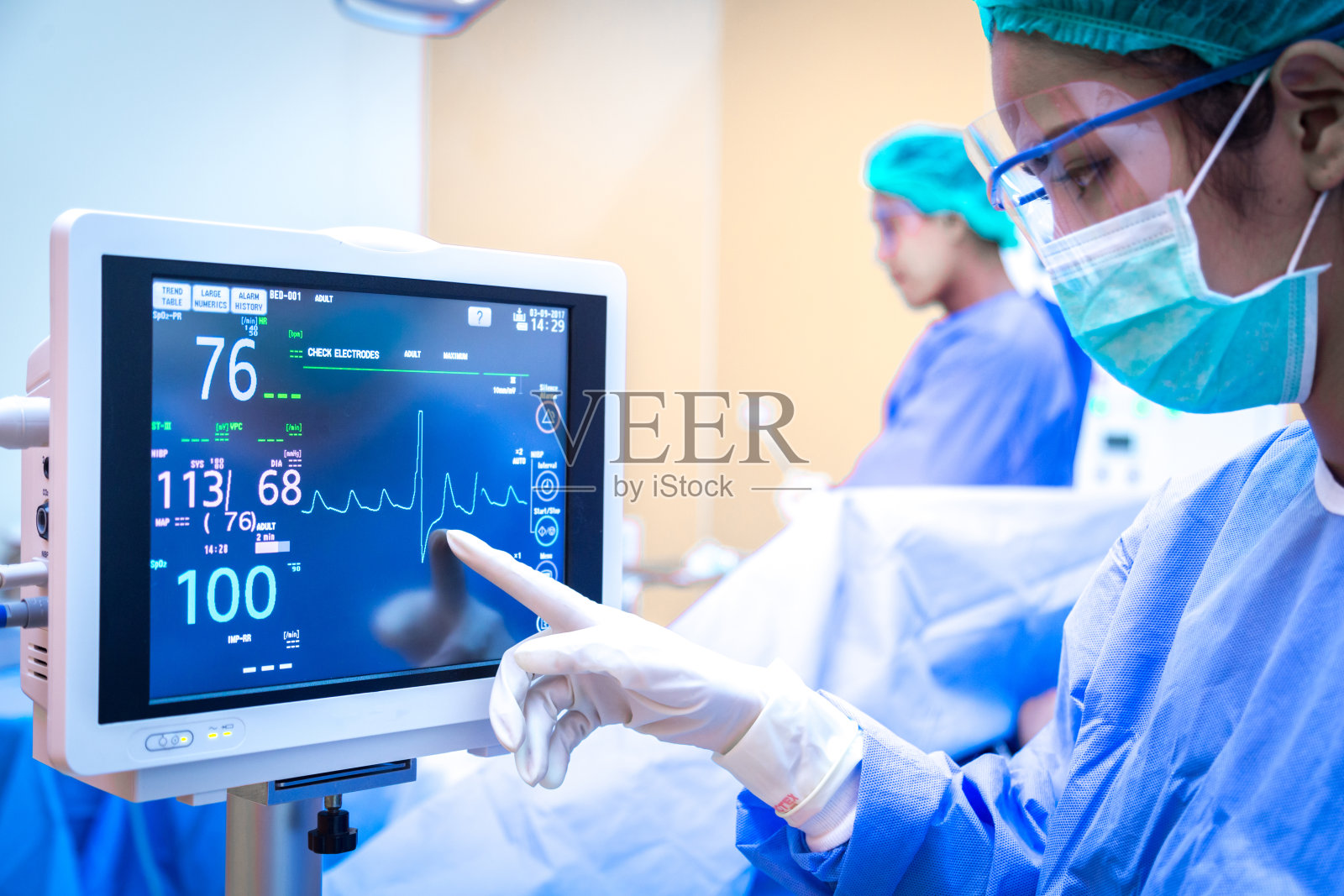 Female surgeon using monitor in operating room.照片摄影图片