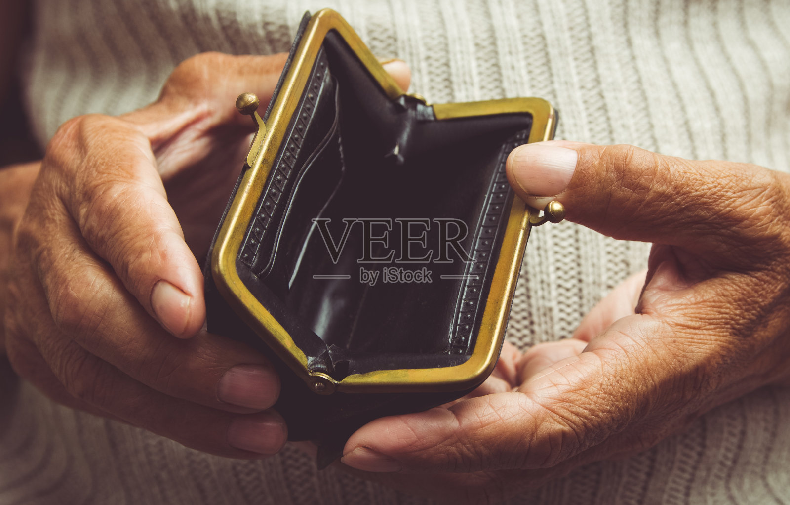 一位老人手里拿着一个空钱包。皱巴巴的手握着复古空钱包。贫困的退休概念。特殊的爽肤水照片摄影图片