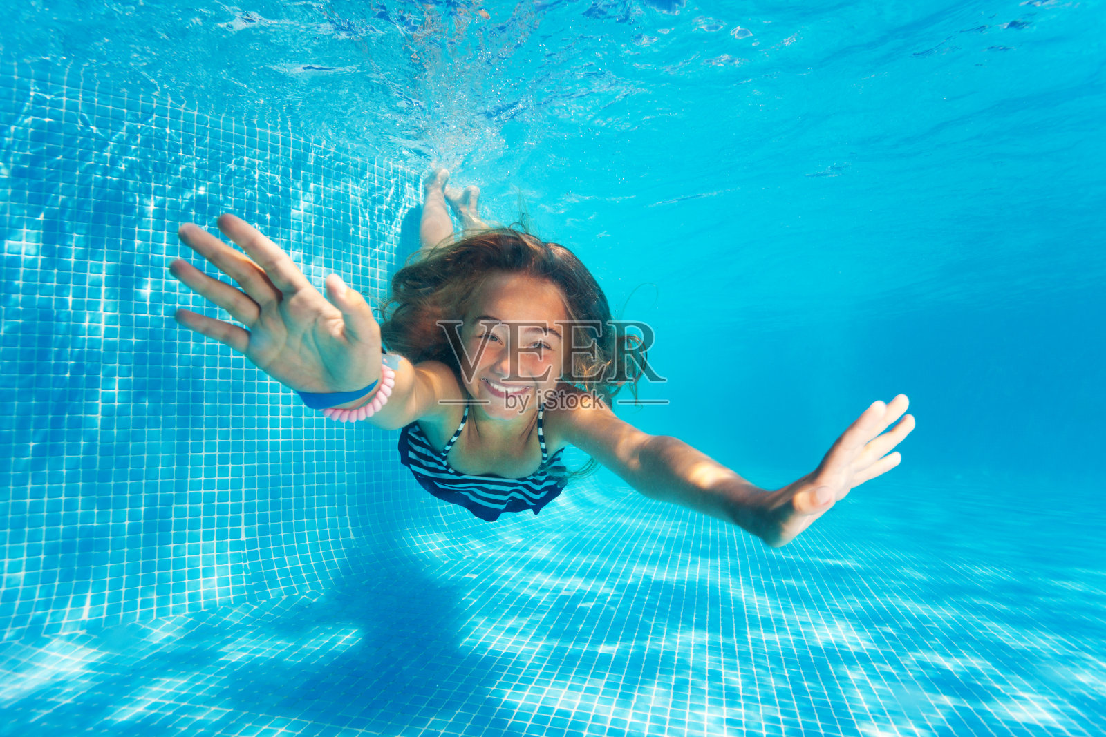 肖像的十岁前女孩跳水与乐趣在游泳池照片摄影图片