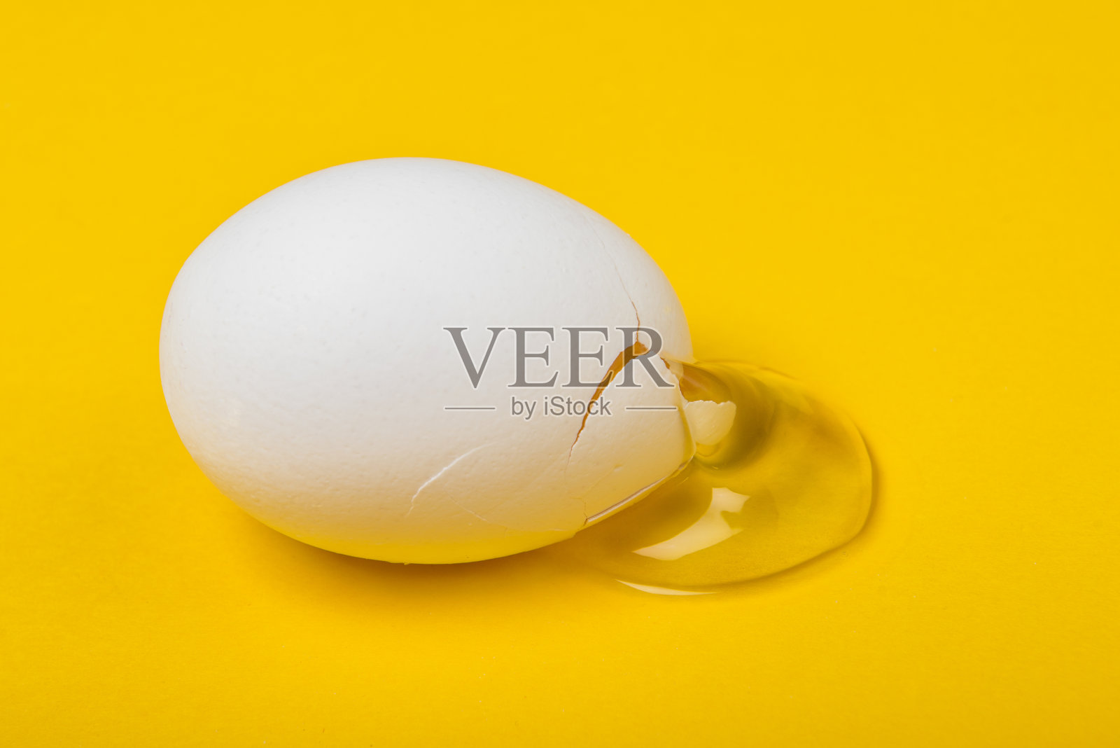 高角度的破裂的白色鸡蛋与它的蛋黄在黄色的背景照片摄影图片