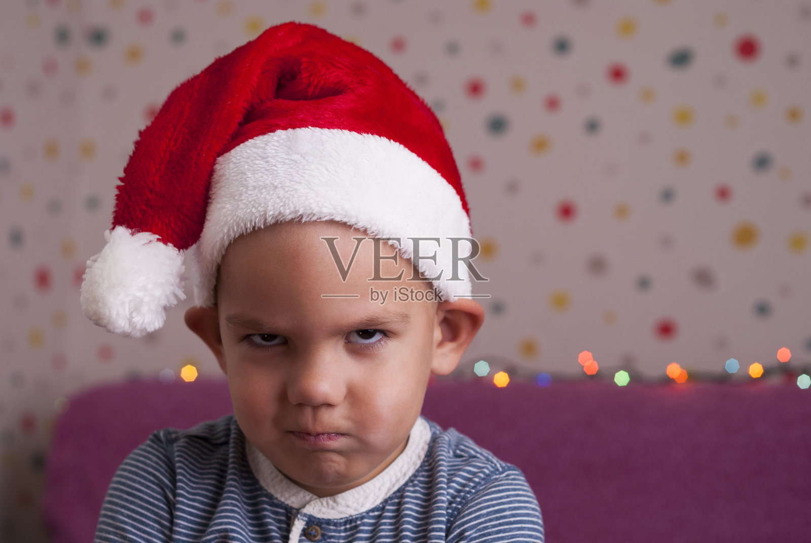 戴着圣诞老人帽的愤怒男孩照片摄影图片