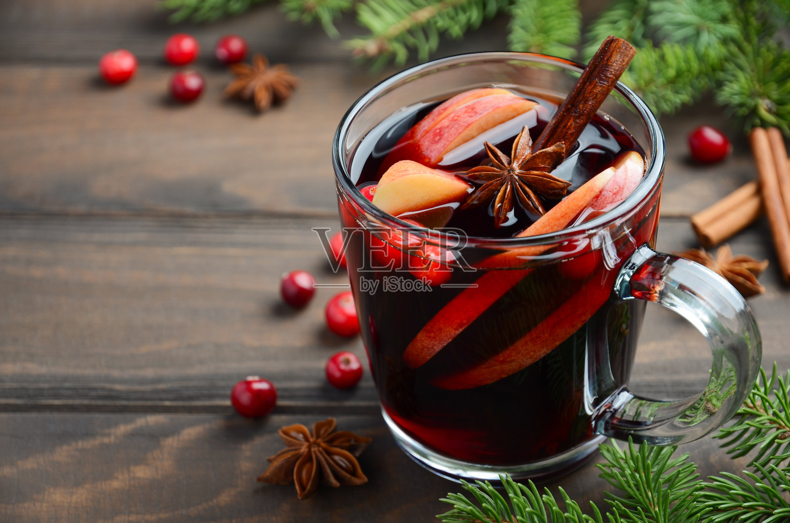 圣诞热葡萄酒与苹果和蔓越莓。用冷杉枝，蔓越莓和香料装饰的假日概念。照片摄影图片