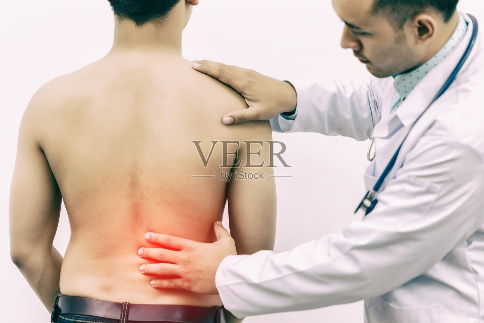 医生在医院用听诊器触摸背部钢板，以确定背部疼痛的原因。体检的概念，医疗保健。照片摄影图片