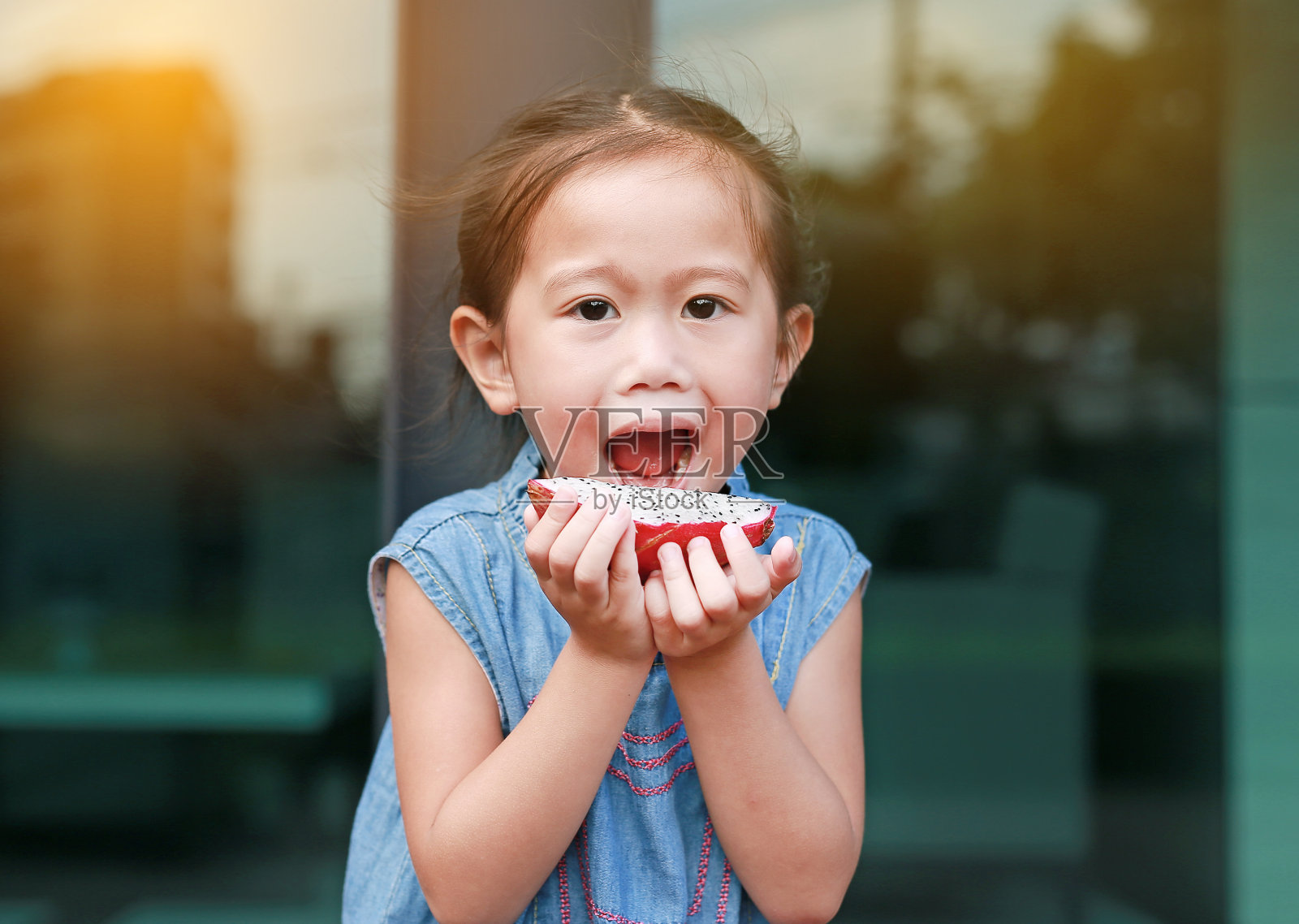 特写小女孩正在吃火龙果片。照片摄影图片