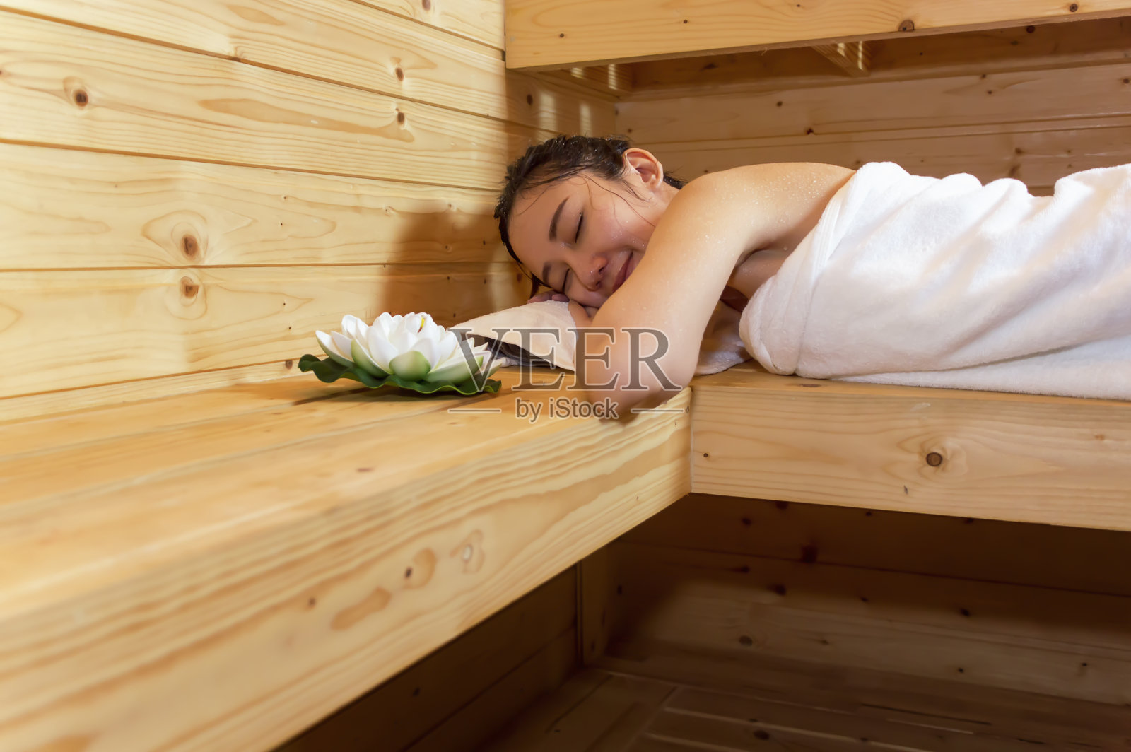 美丽的年轻亚洲女孩睡觉放松，躺在桑拿房的桑拿舱。照片摄影图片