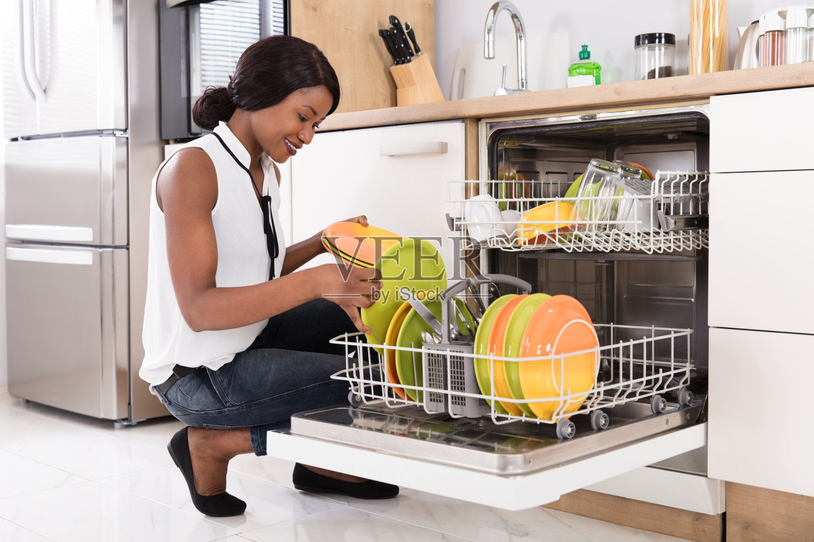 在洗碗机里整理盘子的女人照片摄影图片