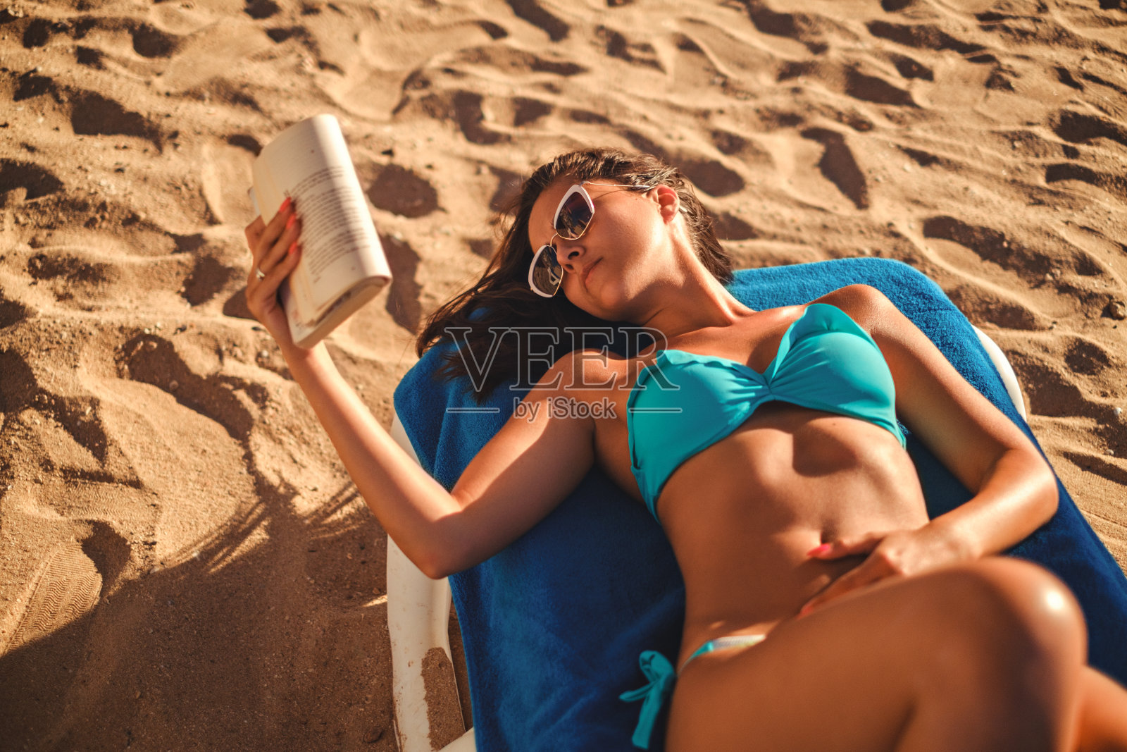 女孩躺在沙滩上看书照片摄影图片