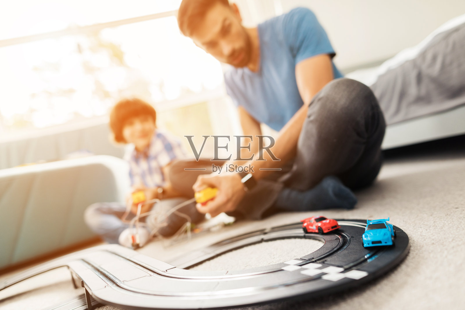 父亲和儿子用孩子们的汽车比赛。照片摄影图片