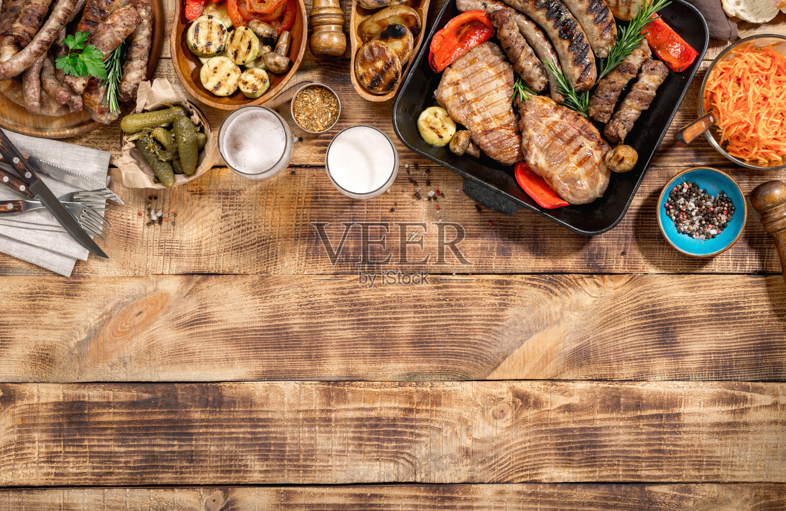 开胃的烧烤牛排，香肠，啤酒和烤蔬菜在木制的野餐桌上照片摄影图片
