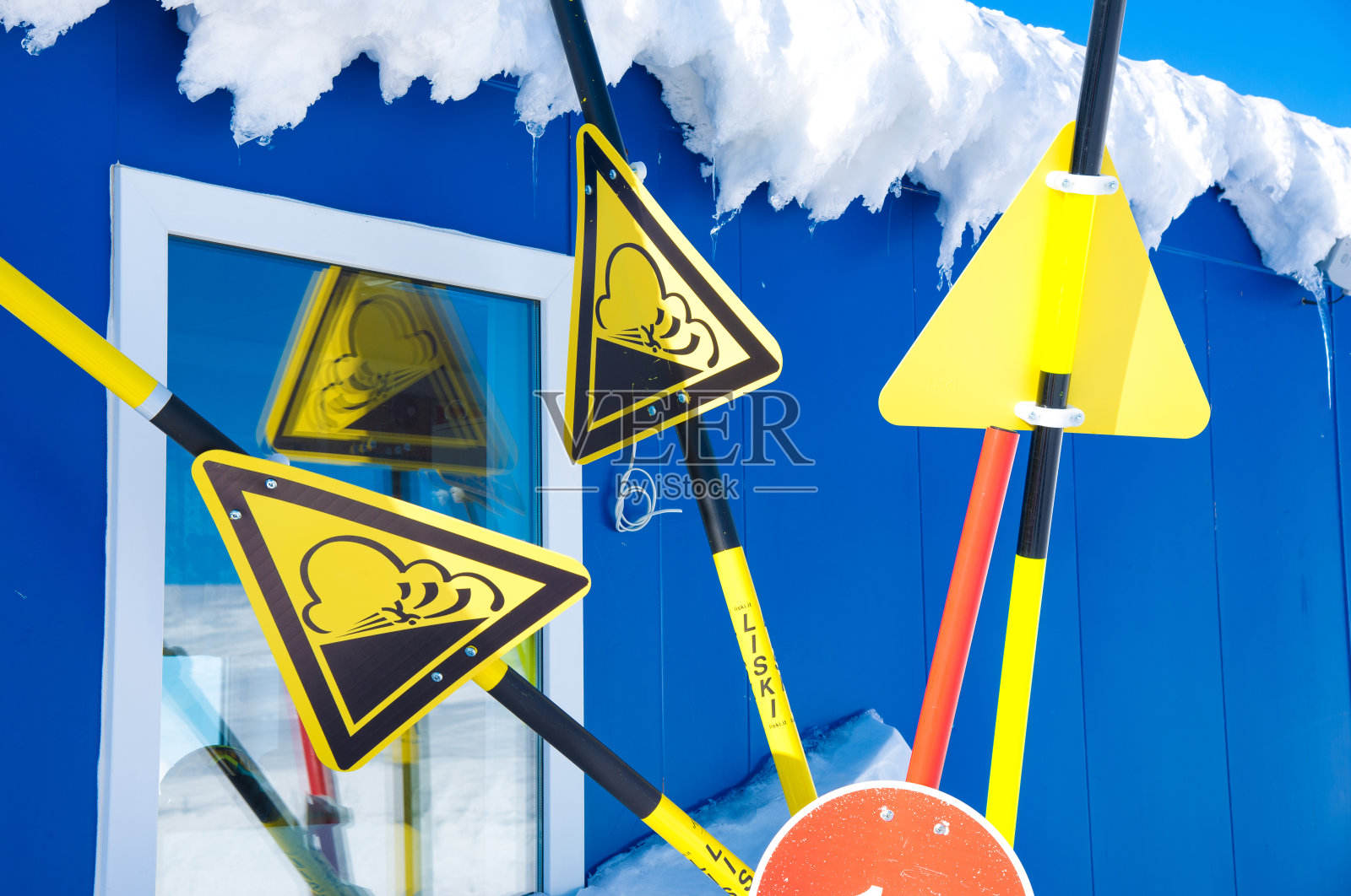 滑雪胜地的雪崩危险标志。有关滑坡和无越野滑雪的信息。蓝色天空背景上的黄色三角形。俄罗斯,Khibiny山脉。照片摄影图片