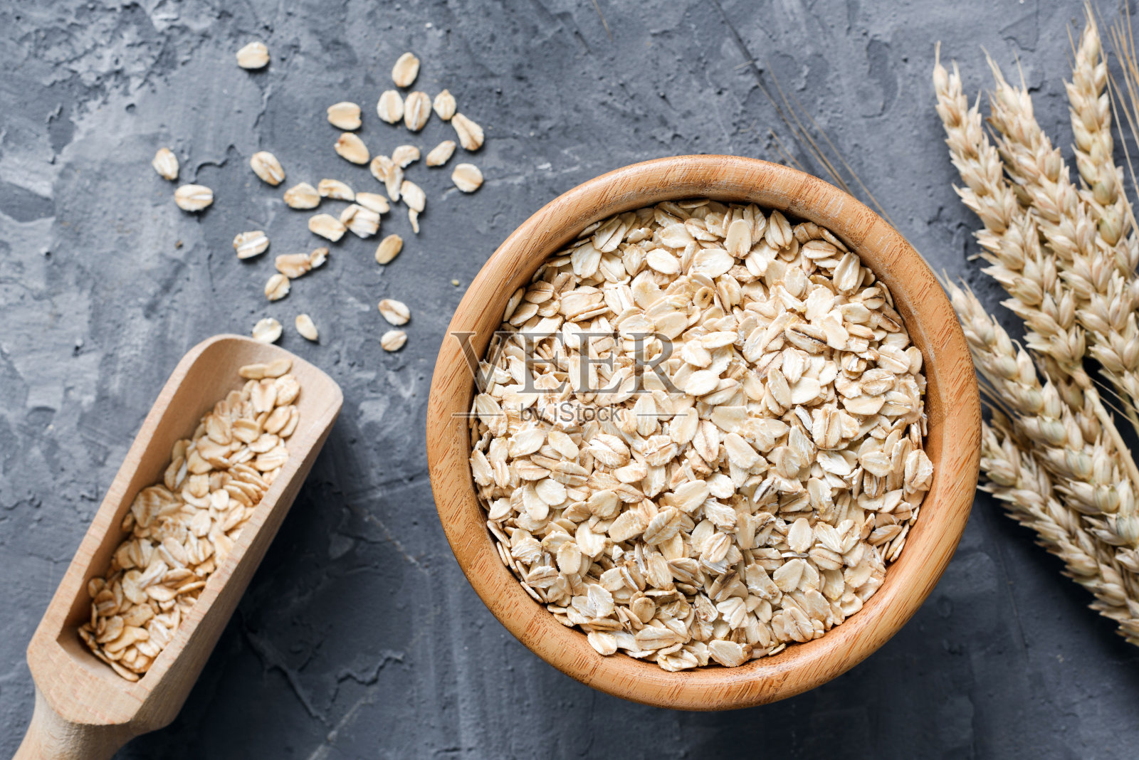 燕麦卷或燕麦片在木碗石背景。照片摄影图片