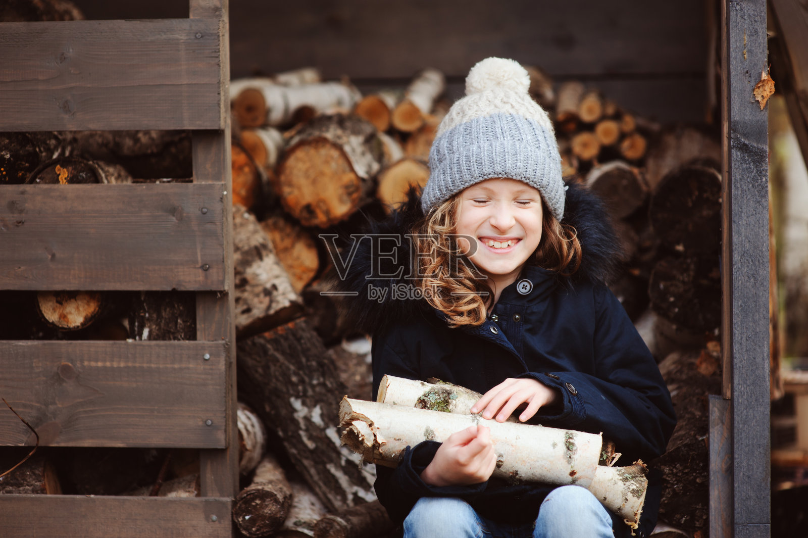 快乐的童女在冬天或秋天从棚子里捡柴火照片摄影图片