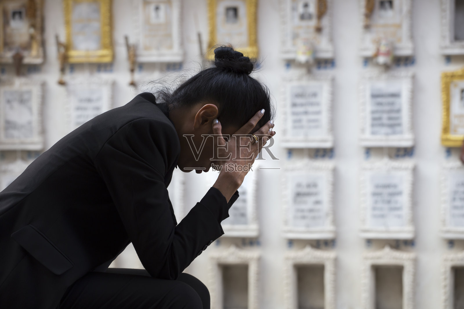 一个悲伤的女人坐在坟墓旁边照片摄影图片