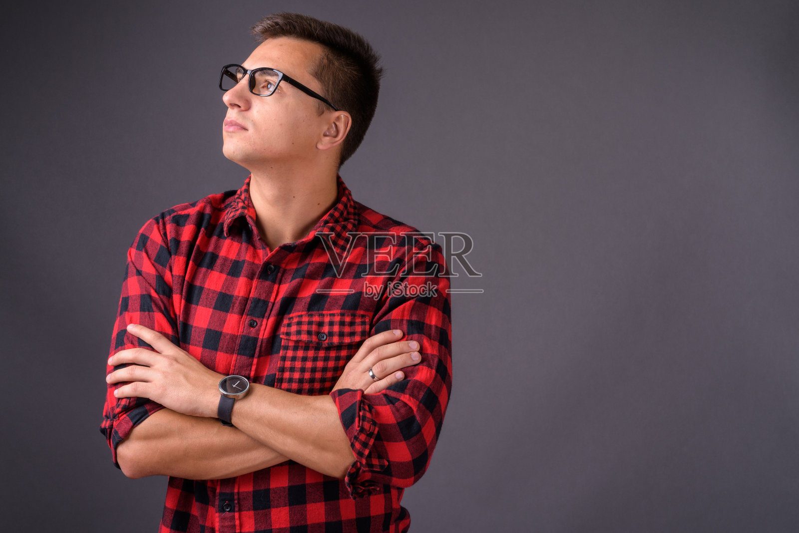 年轻英俊的男子穿着红色格子衬衫和眼镜在灰色的背景照片摄影图片