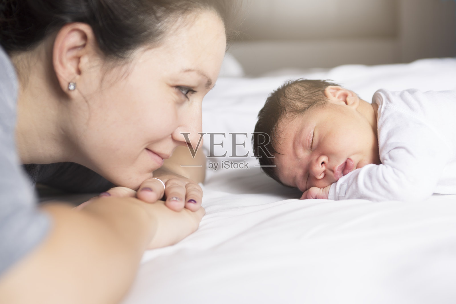 快乐的妈妈和宝宝躺在家里的床上照片摄影图片