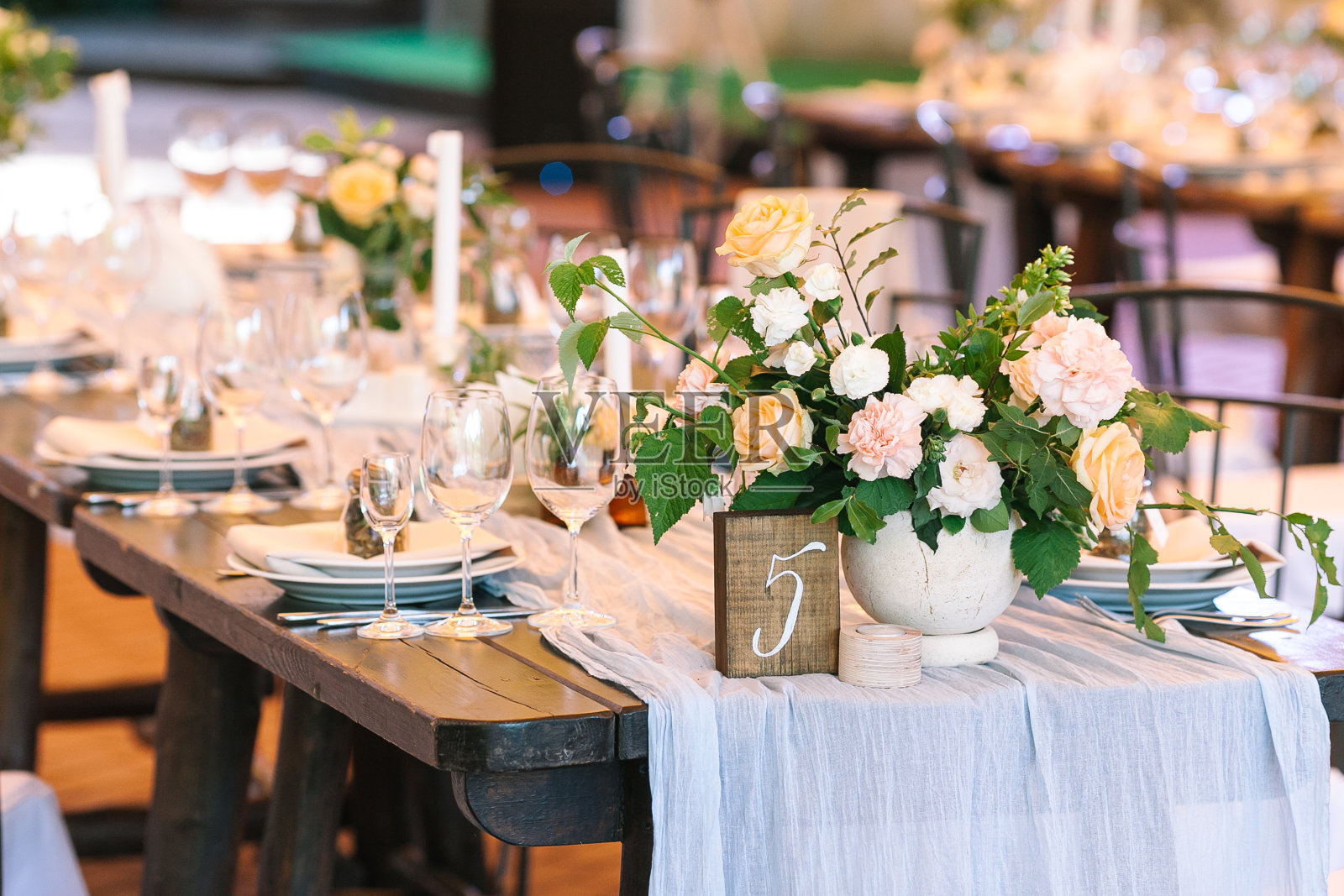 假日、兴奋、服务理念。五号餐桌上摆放着洁白的盘子、透明的酒杯、银制餐具和华丽的玫瑰花束照片摄影图片