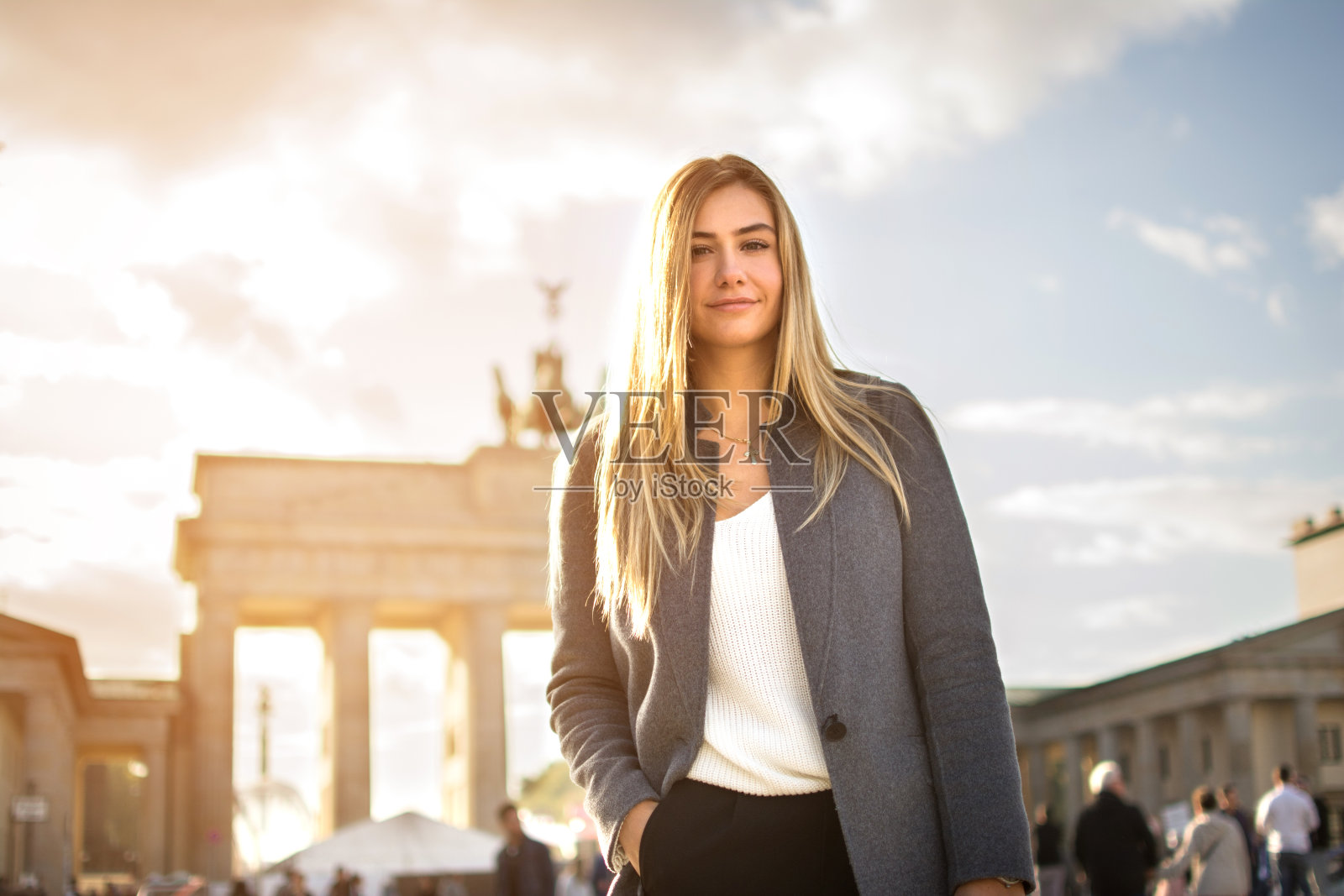在德国柏林勃兰登堡门前微笑的时尚年轻女人的肖像。照片摄影图片