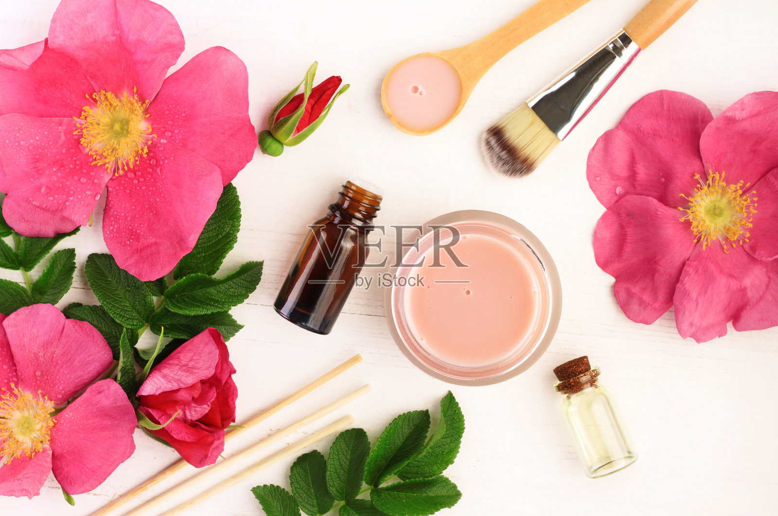 粉红色的新鲜野生玫瑰花和叶子，瓶子和罐子，俯视图。照片摄影图片