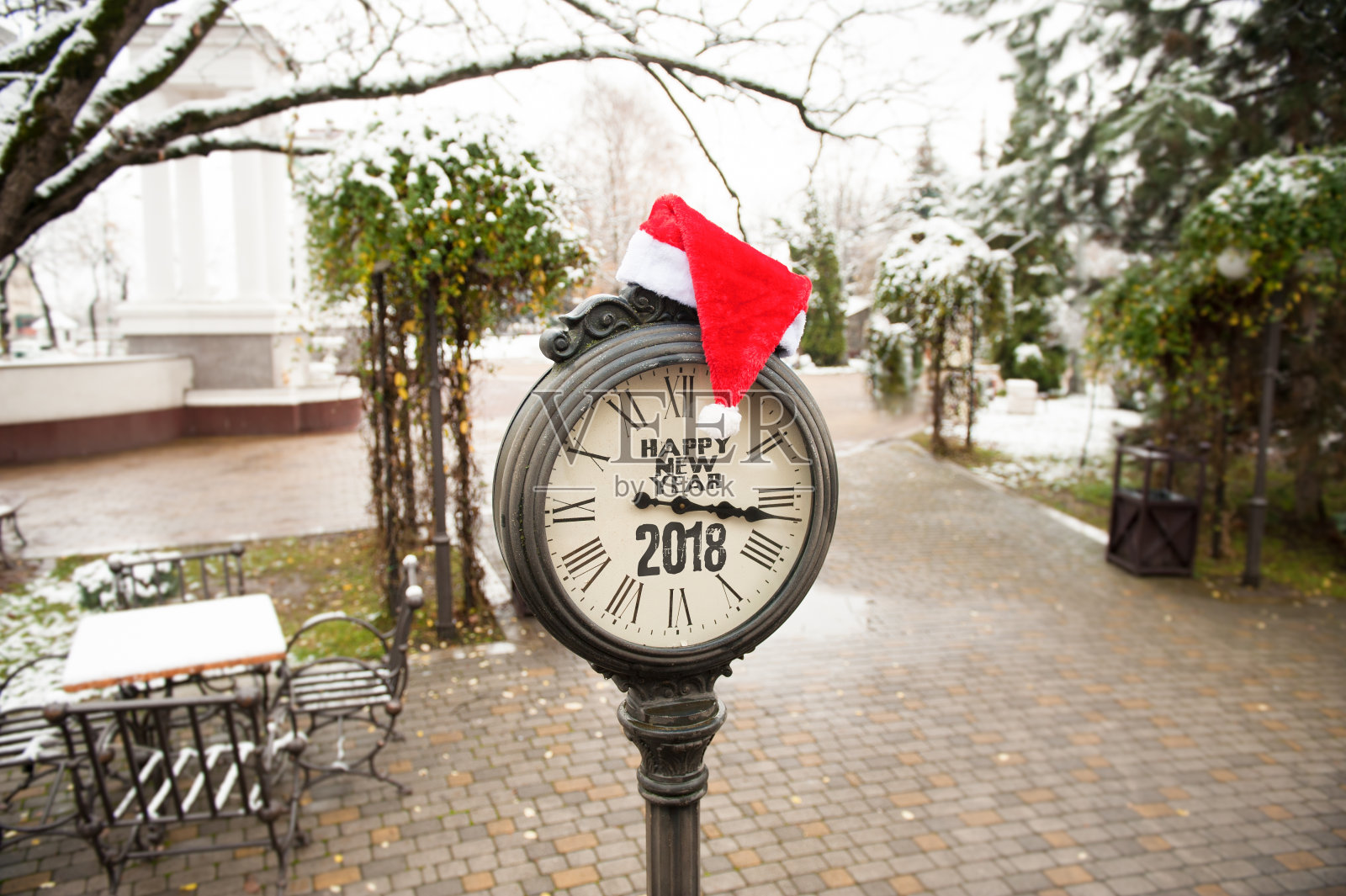 小镇公园里挂着“2018年新年快乐”的复古街道钟，上面戴着圣诞老人帽照片摄影图片