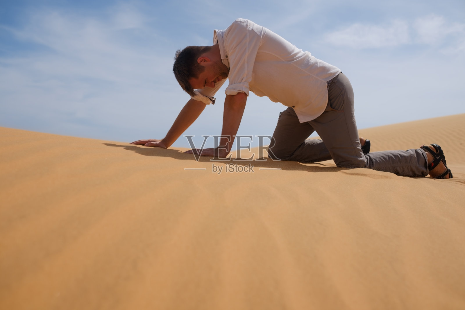 一个人独自走在阳光明媚的沙漠里。他迷了路，上气不接下气。没有水和能源。照片摄影图片