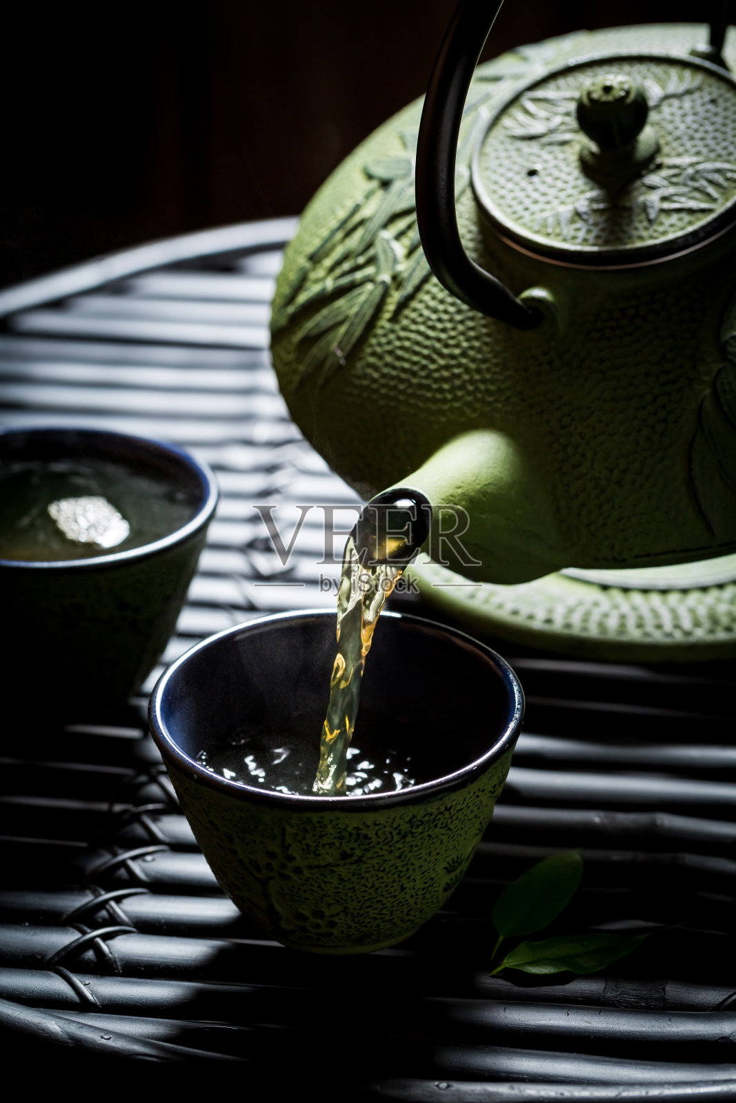 用茶壶将绿茶倒入茶杯中照片摄影图片