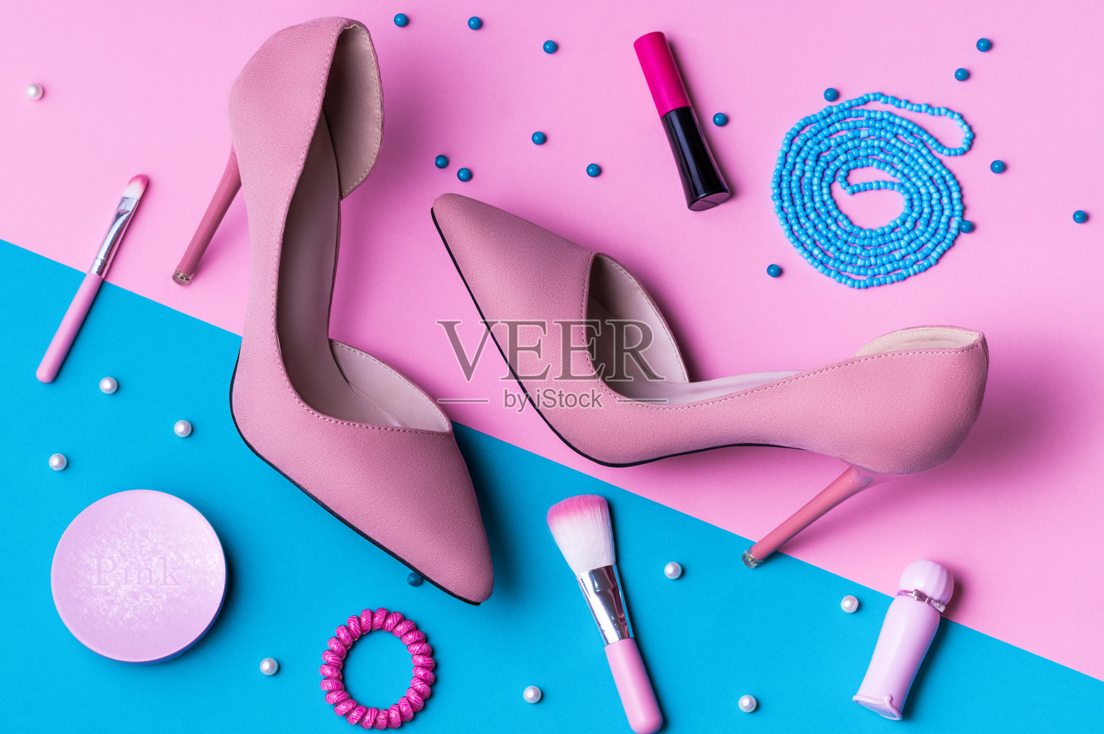 粉色绒面革高跟鞋在粉红色和蓝色分裂的背景与配件。照片摄影图片