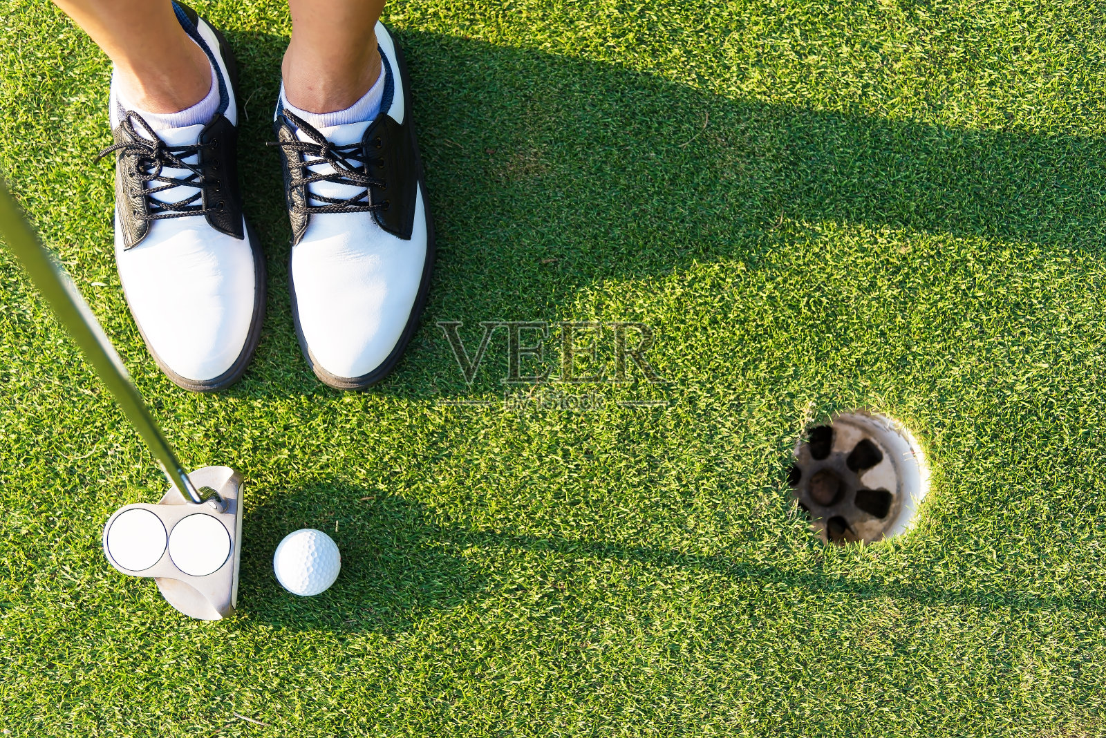 近距离的推杆打高尔夫球洞在球场。顶视图的高尔夫球手照片摄影图片