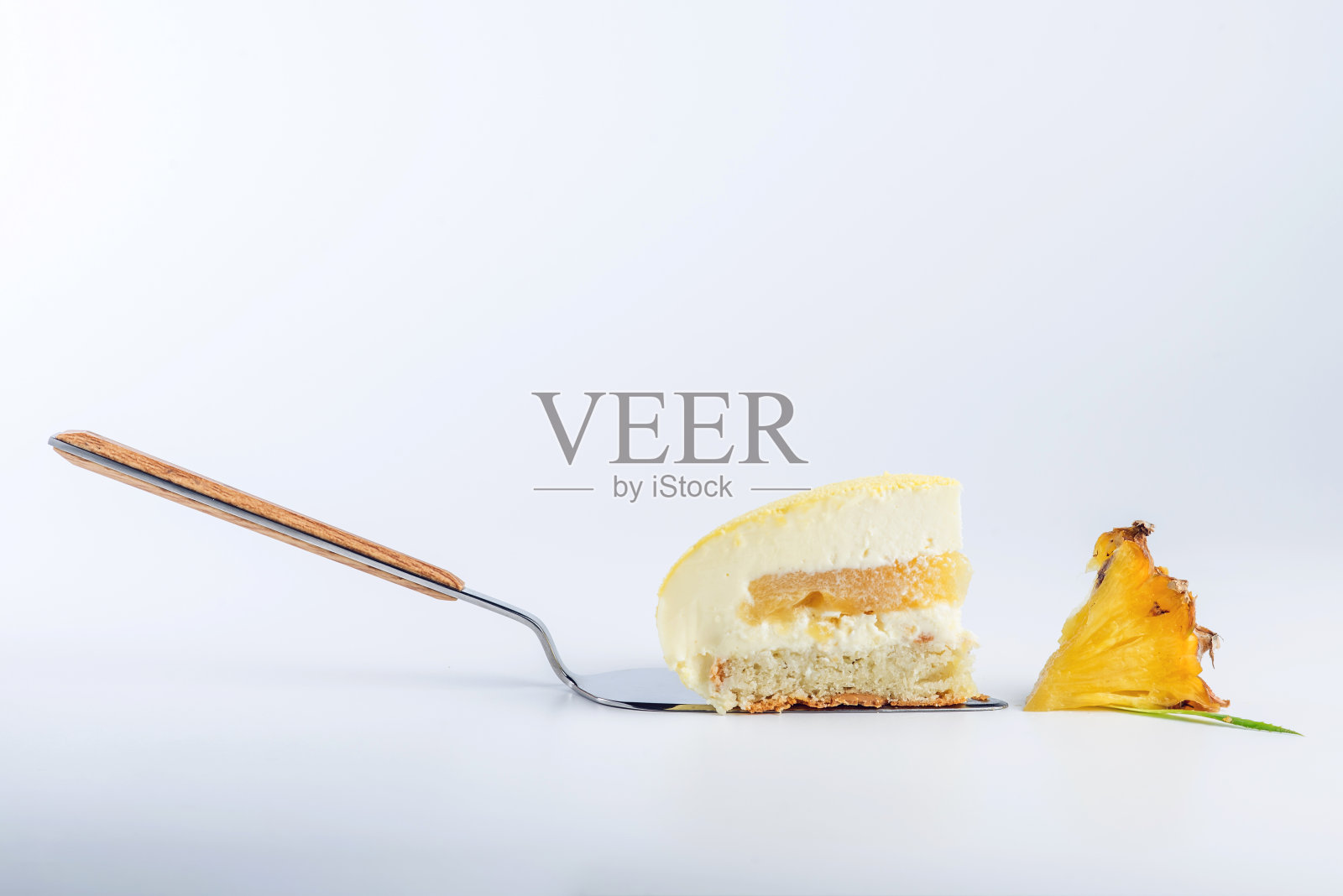 一块黄色的蛋糕，里面有白色的蛋奶酥，饼干和菠萝。概念设计的甜点照片摄影图片