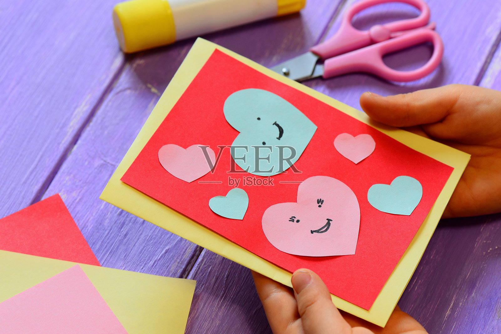 孩子手里拿着一张情人节贺卡。孩子正在展示一张贺卡。情人节快乐。简单的纸工艺品为孩子的概念。特写镜头照片摄影图片
