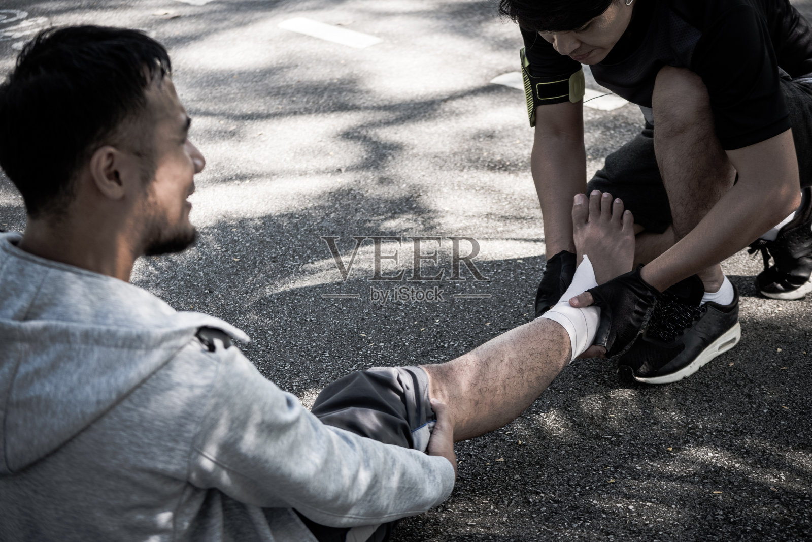 一名男子在公园锻炼后用弹性绷带缓解脚踝疼痛。照片摄影图片