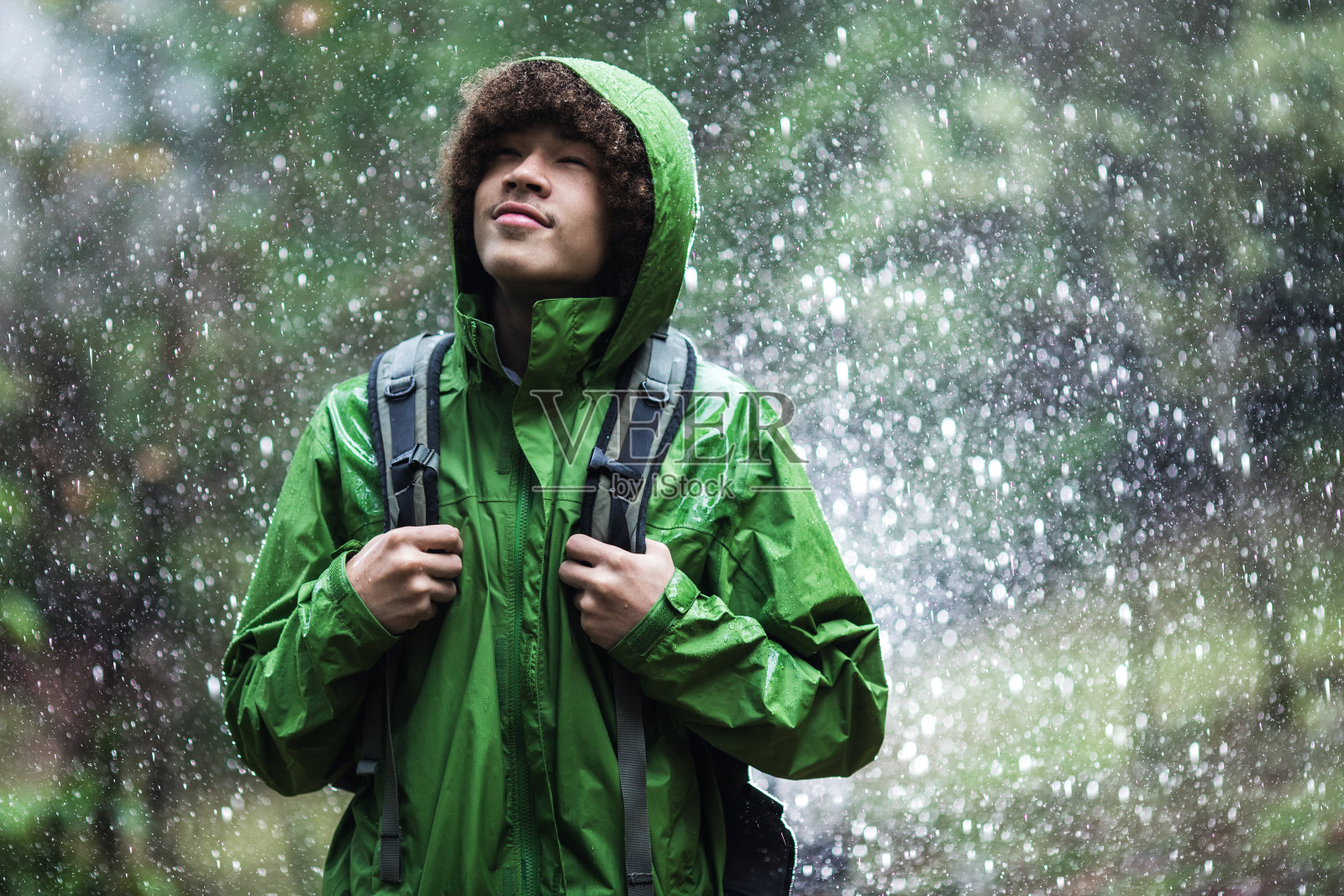 穿着防水夹克在雨中徒步的年轻人照片摄影图片