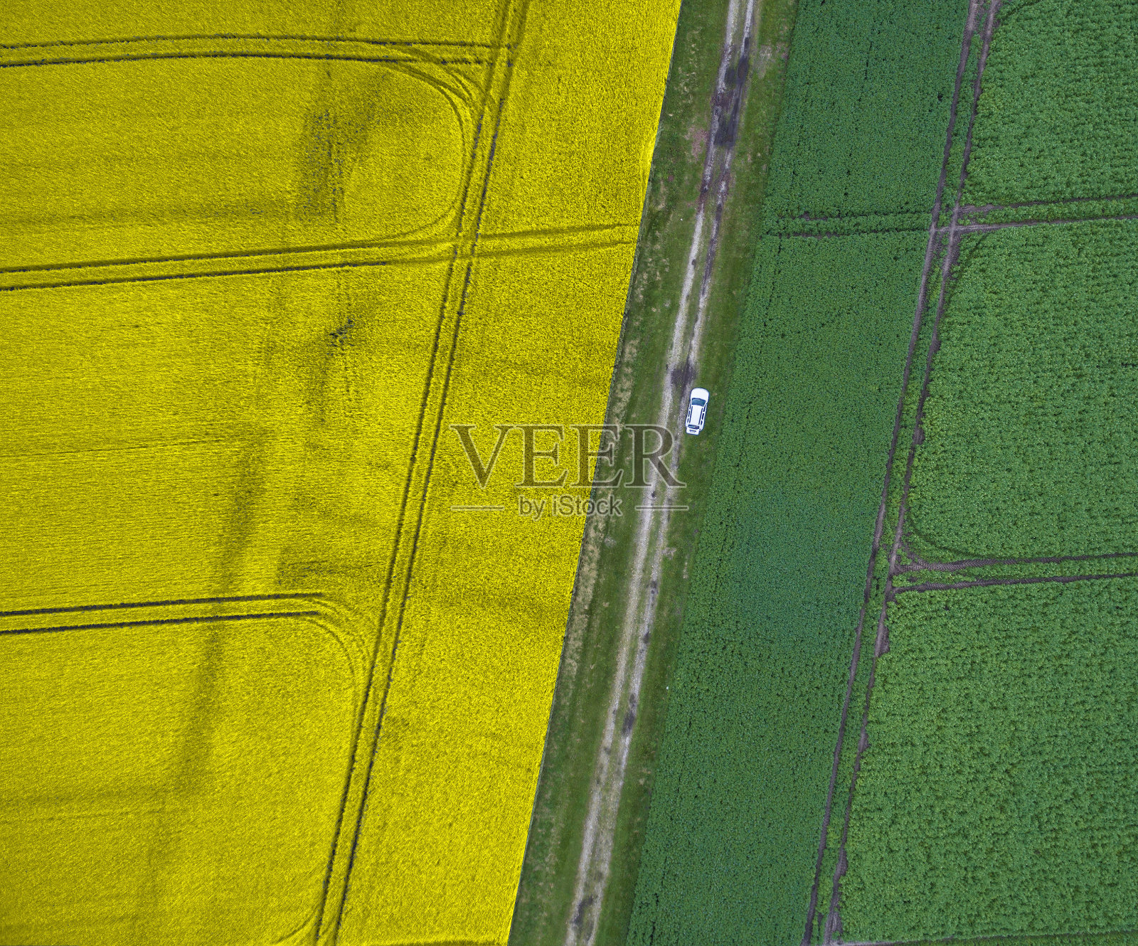 摘要航拍的耕地与一条小路，分割成黄色和绿色一半的耕地。照片摄影图片