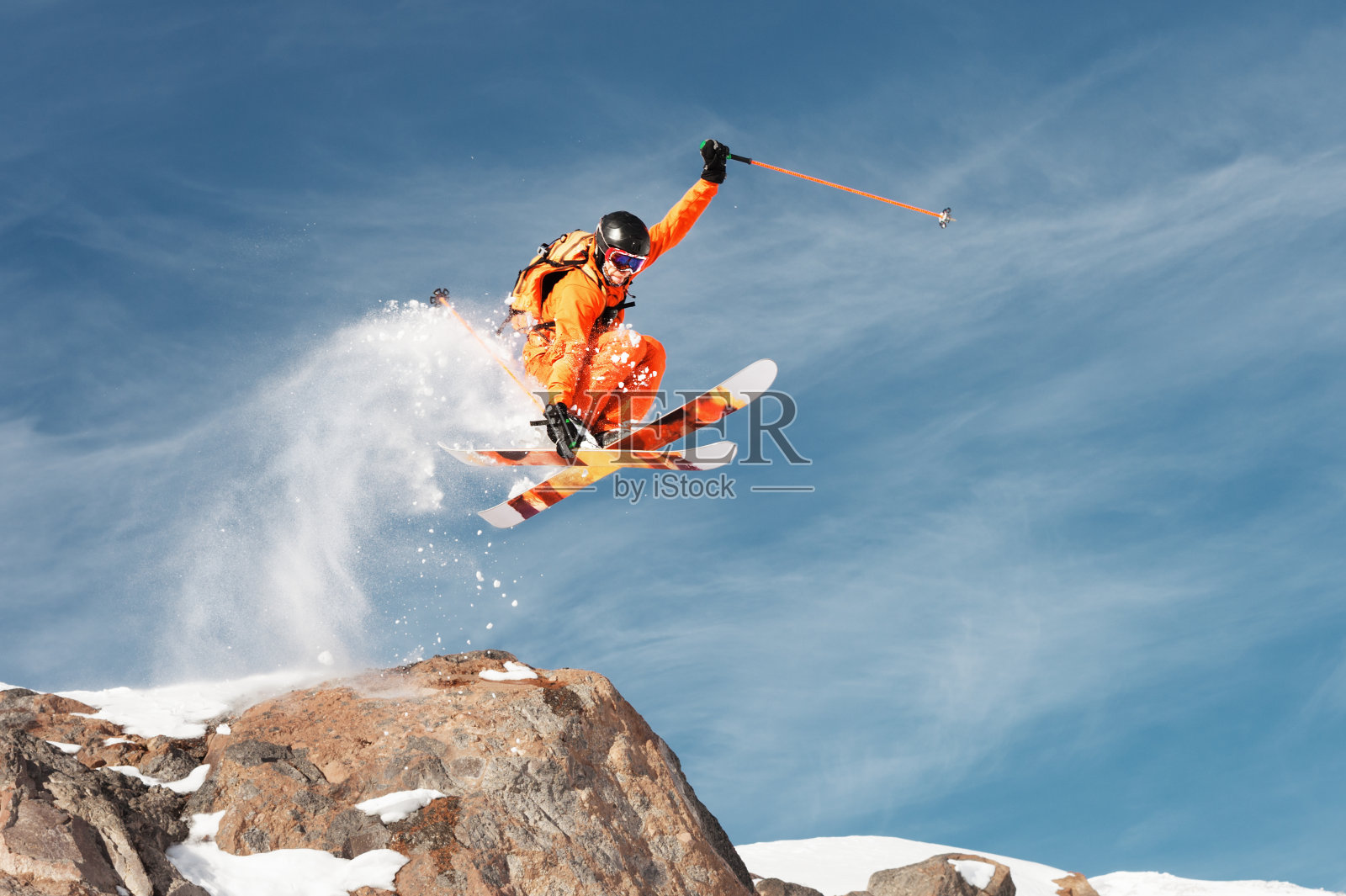 一个滑雪运动员正在山上从一块高高的岩石上跳下来照片摄影图片