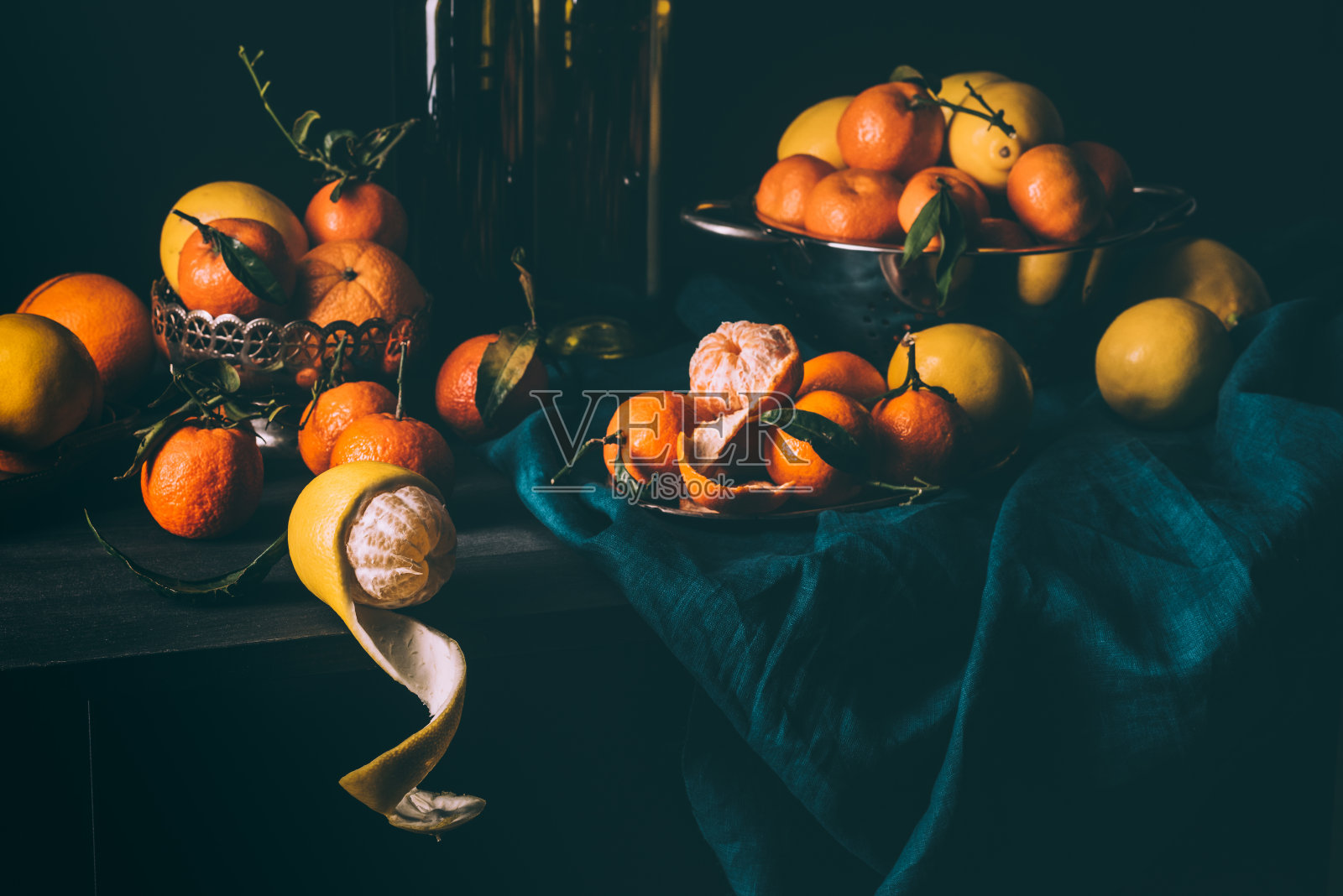 近距离观察新鲜柠檬和橘子的安排在碗和滤网在桌子上与深色桌布照片摄影图片