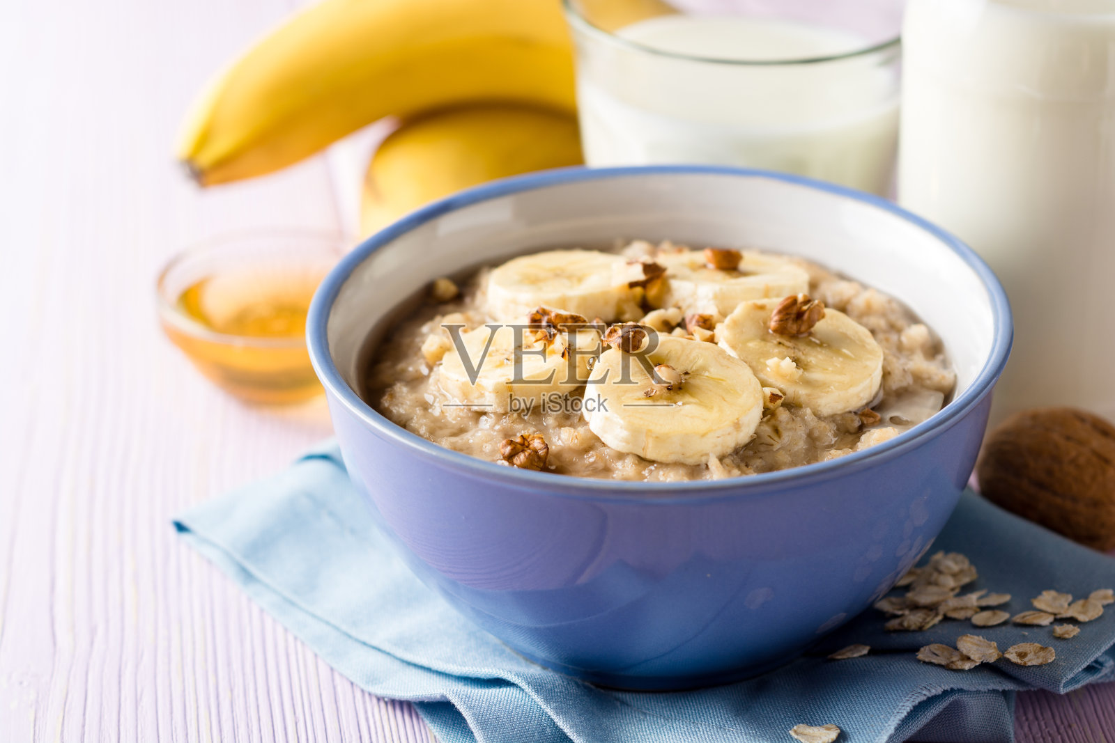 紫木色背景，香蕉、核桃、蜂蜜燕麦粥。健康的早餐。照片摄影图片