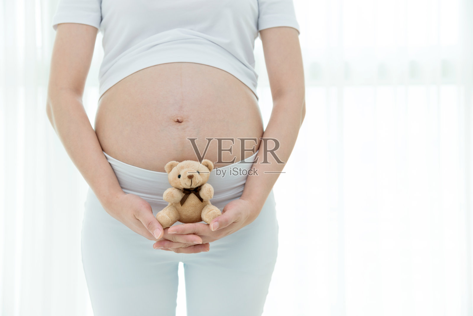 抱着小泰迪熊的孕妇照片摄影图片