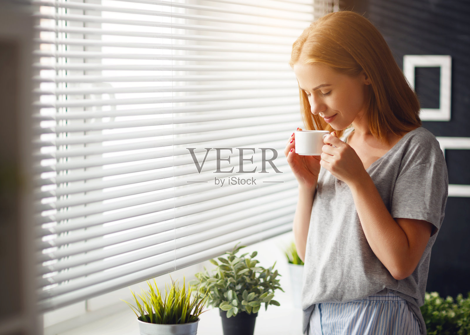 快乐的年轻女子在窗前喝着咖啡迎接早晨照片摄影图片