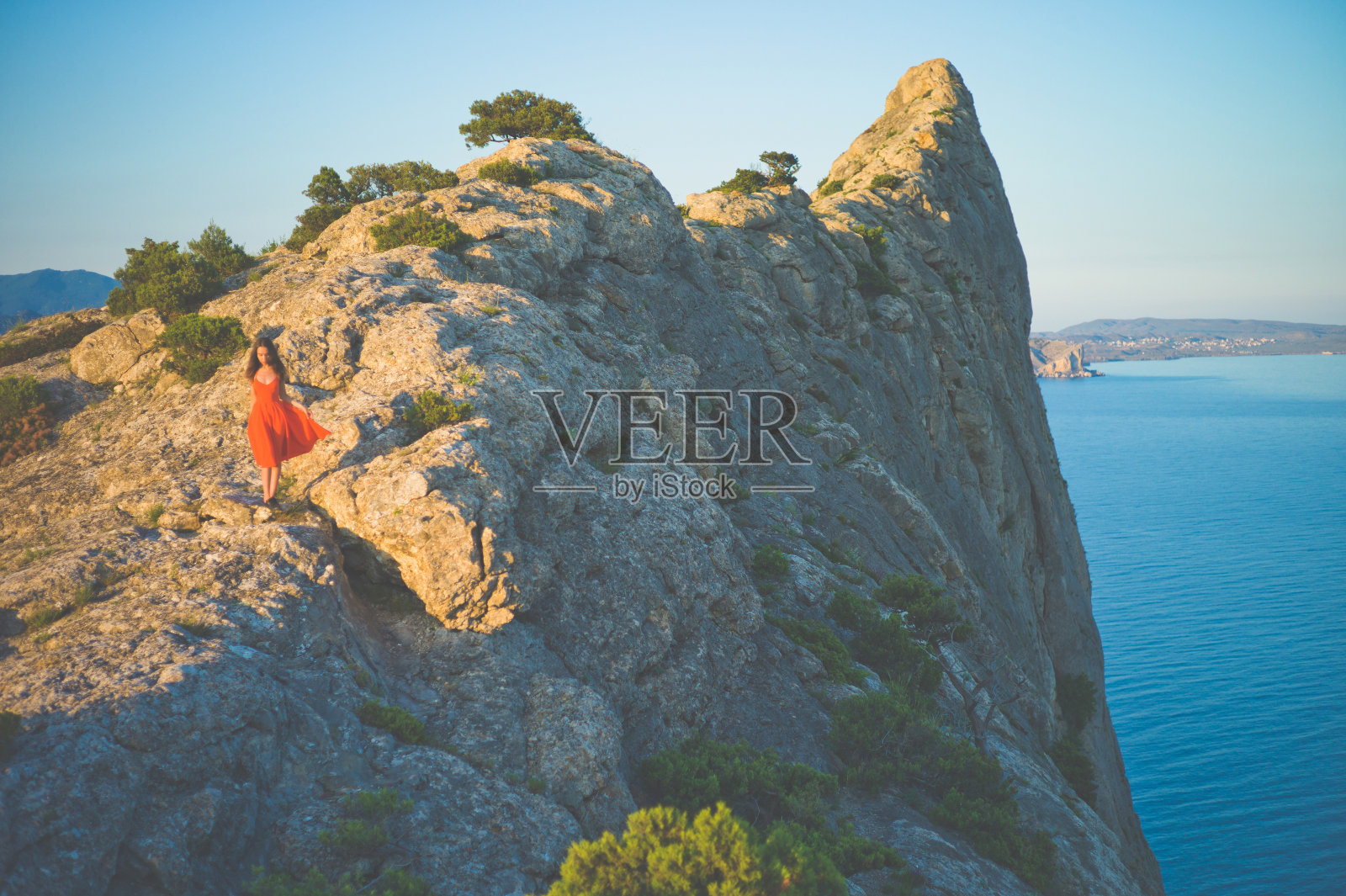 穿红衣服的女人在岩石上走照片摄影图片