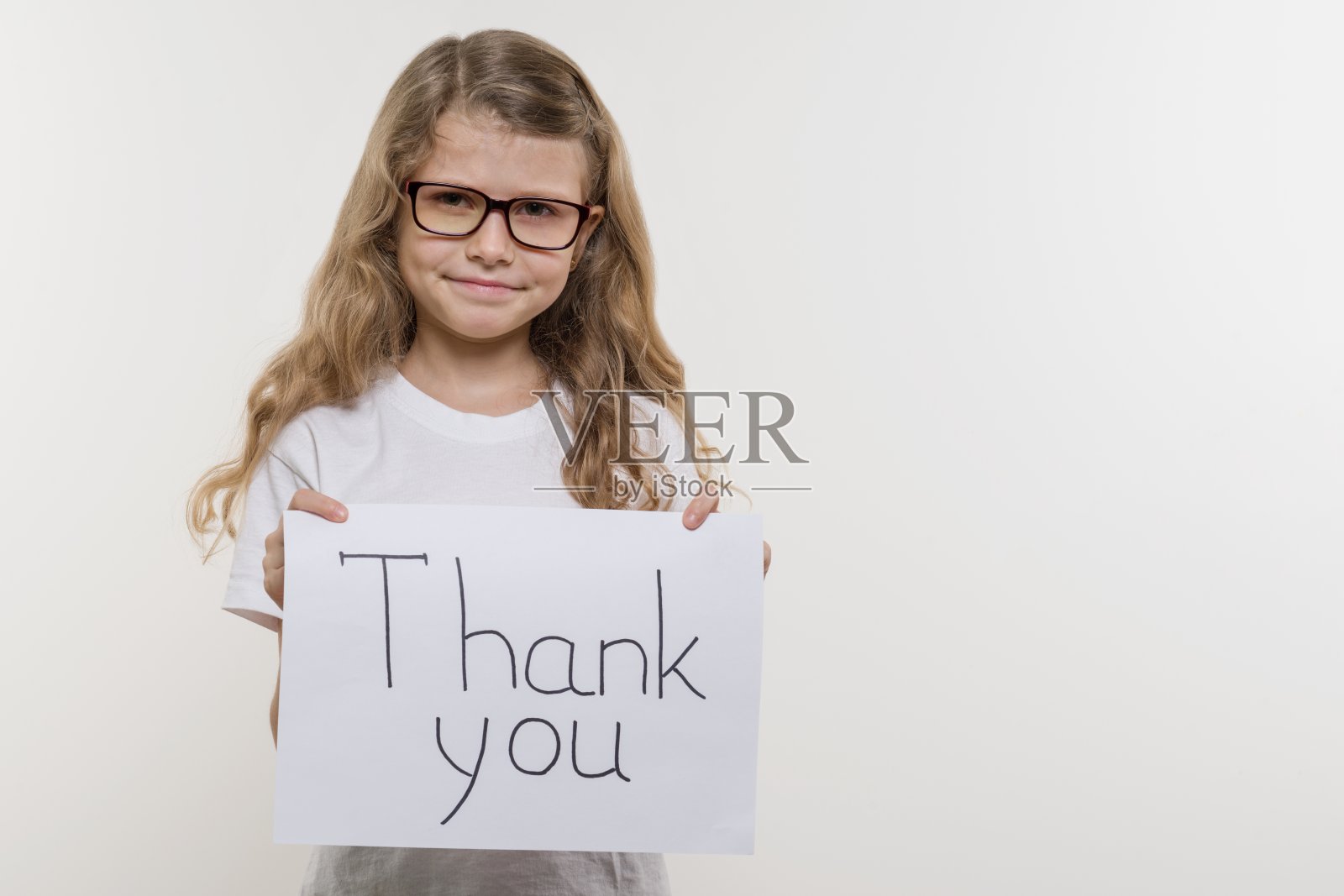 女孩拿着一张纸，上面写着“谢谢你”。白色backgrounde照片摄影图片