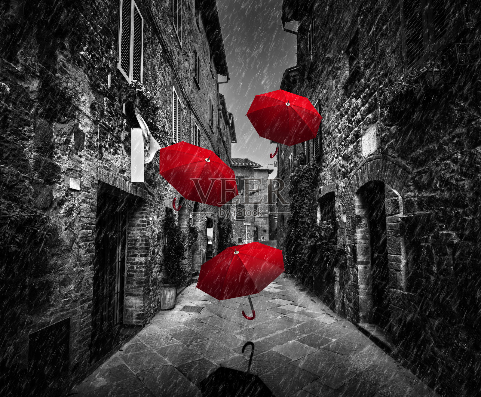 在意大利托斯卡纳的一个古老的意大利小镇上，在黑暗的街道上，伞在风雨中飞舞照片摄影图片