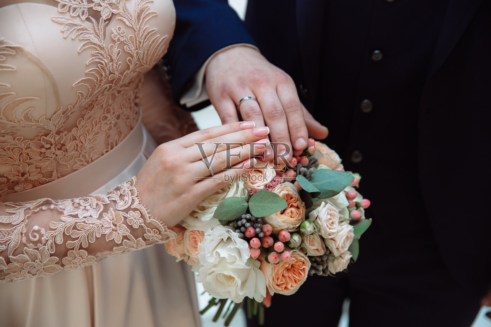 近距离拍摄新郎和新娘在婚礼当天手牵手，展示戒指。爱的家庭观念照片摄影图片