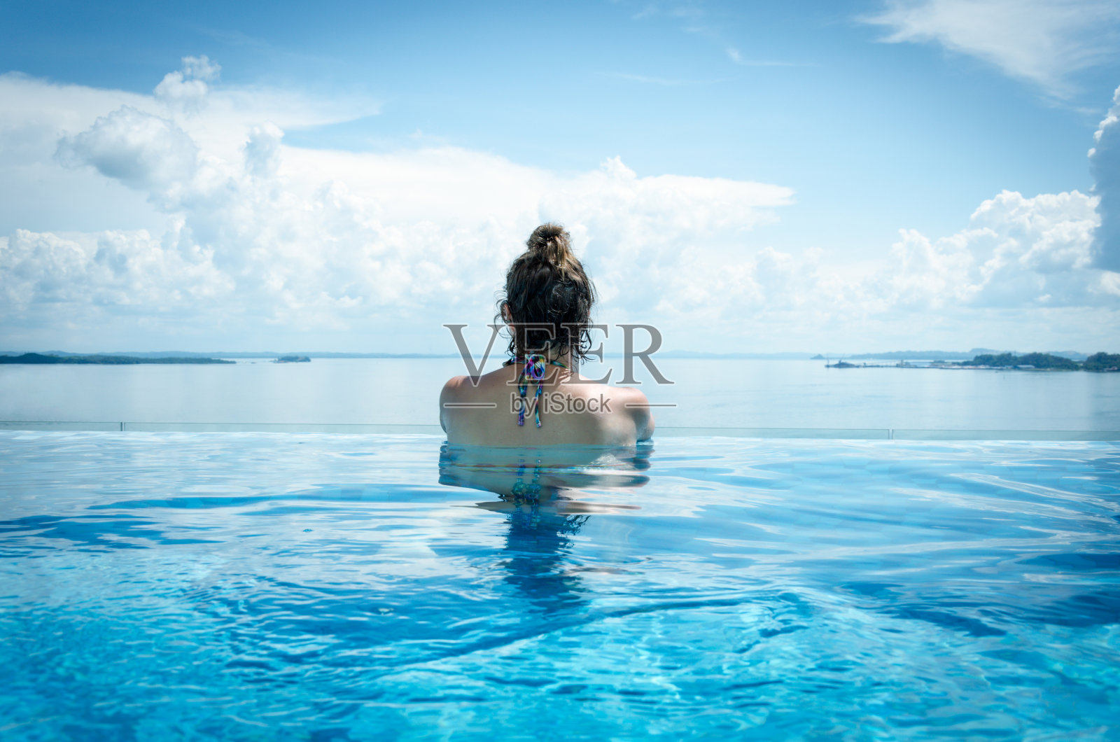 在马来西亚婆罗洲，一名年轻女子在无边泳池中俯瞰大海照片摄影图片